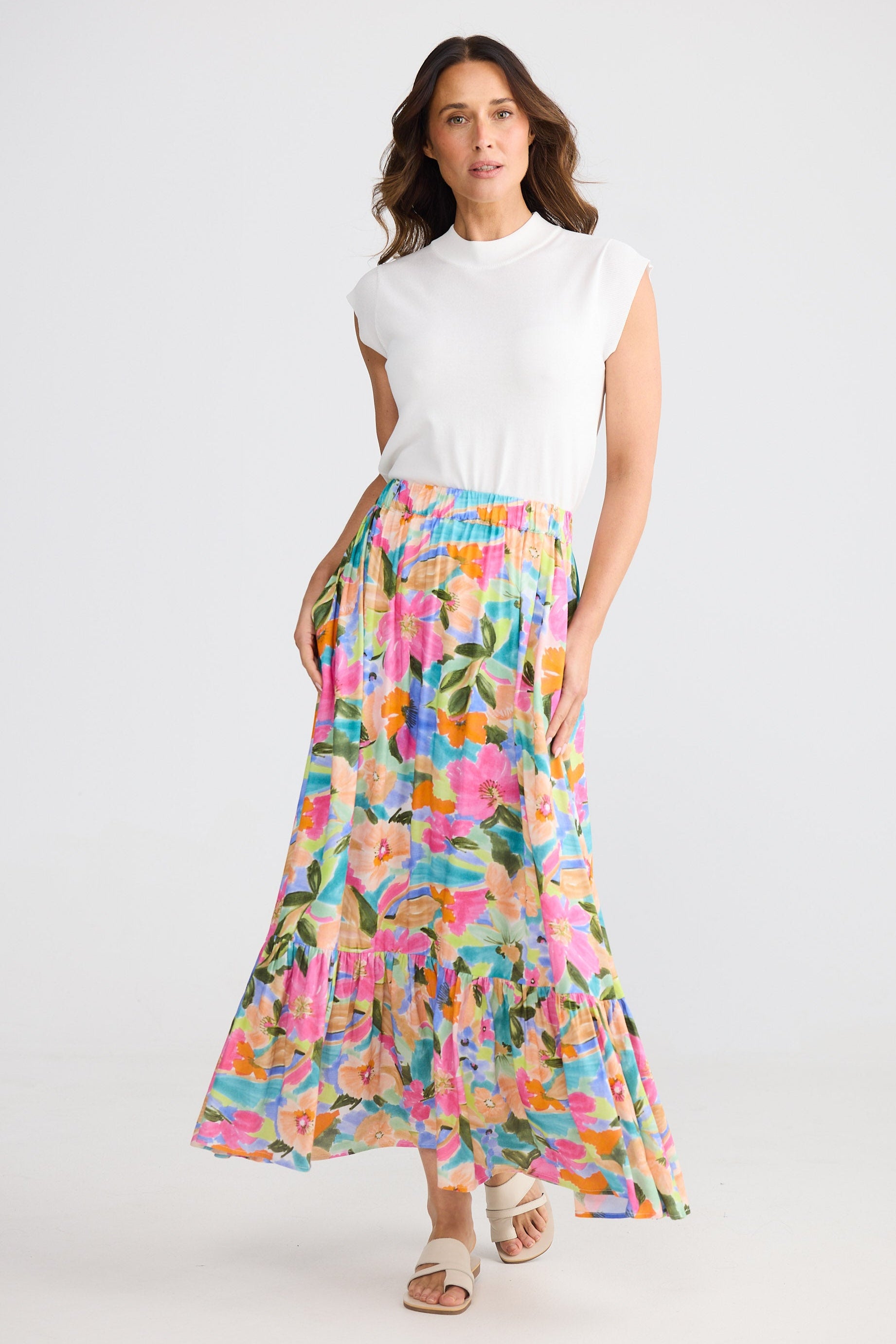 Woman wearing a white top and colorful floral skirt on a white background