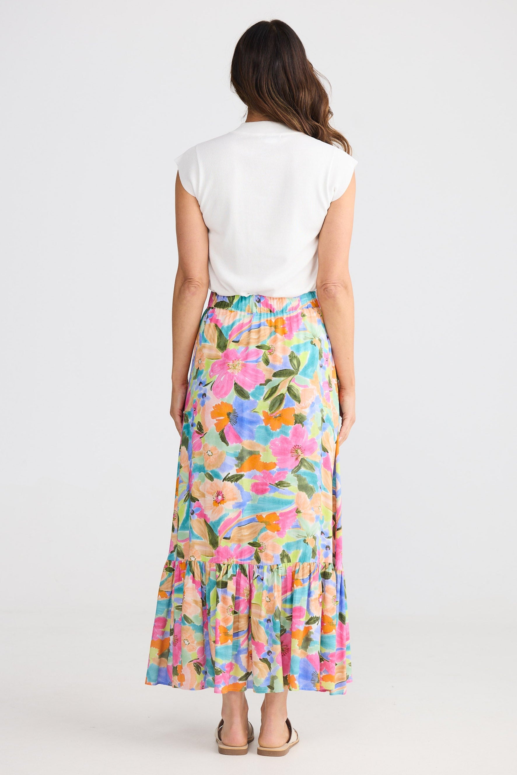 Woman wearing a colorful floral skirt and white top on a white background