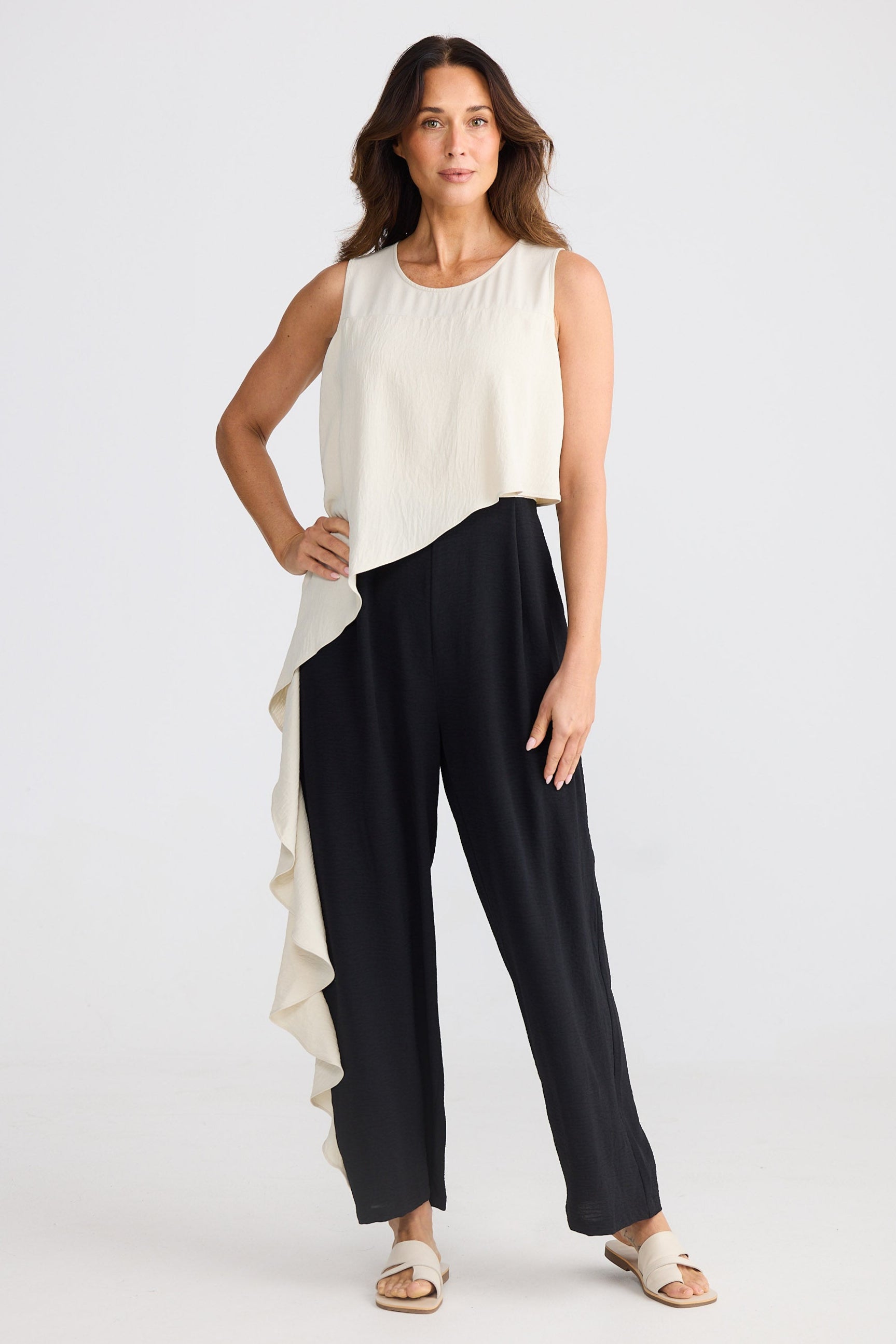 Woman wearing a beige and black sleeveless pantsuit on a white background