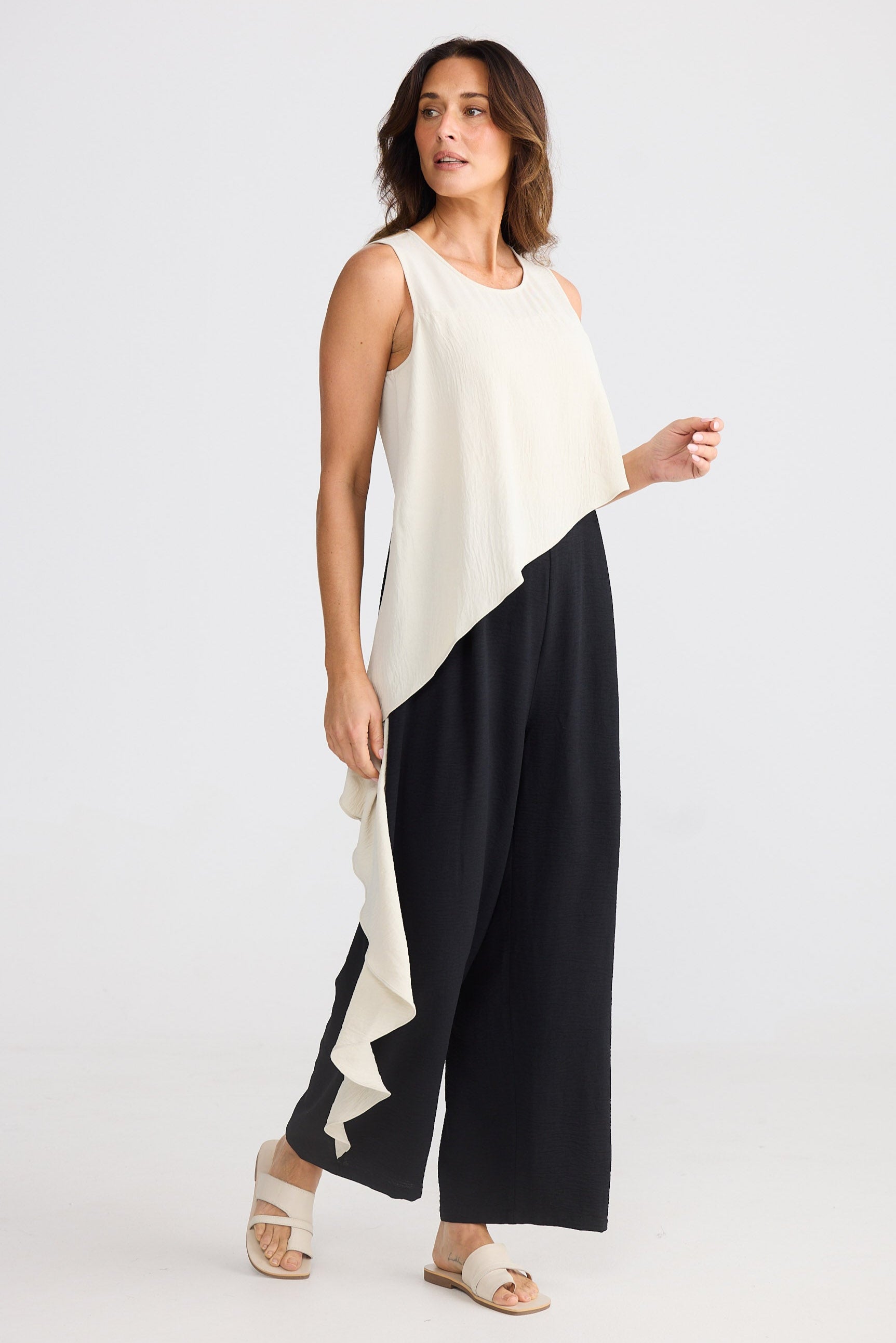 Woman wearing a beige and black sleeveless pantsuit on a white background