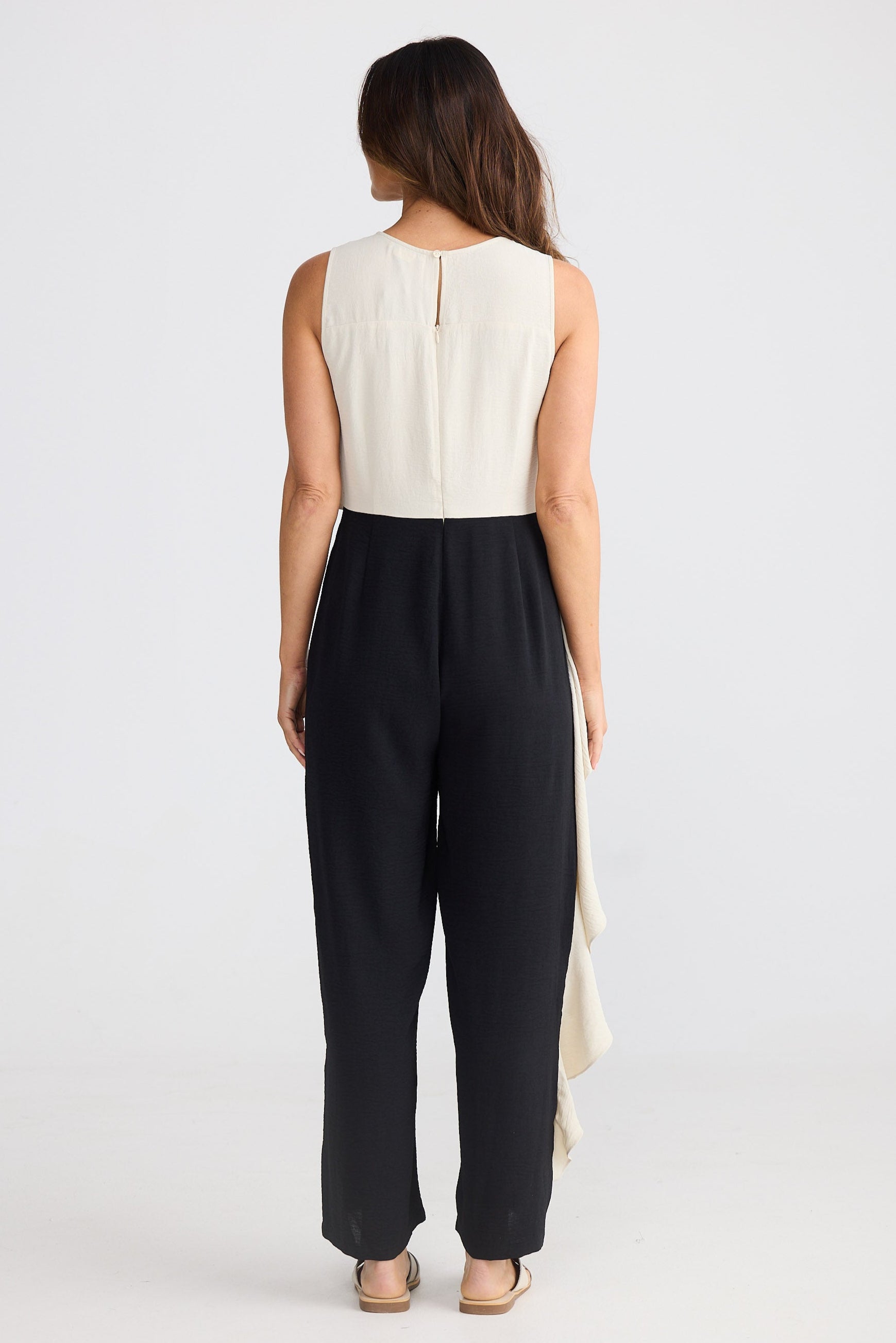 Woman wearing a beige and black sleeveless pantsuit on a white background