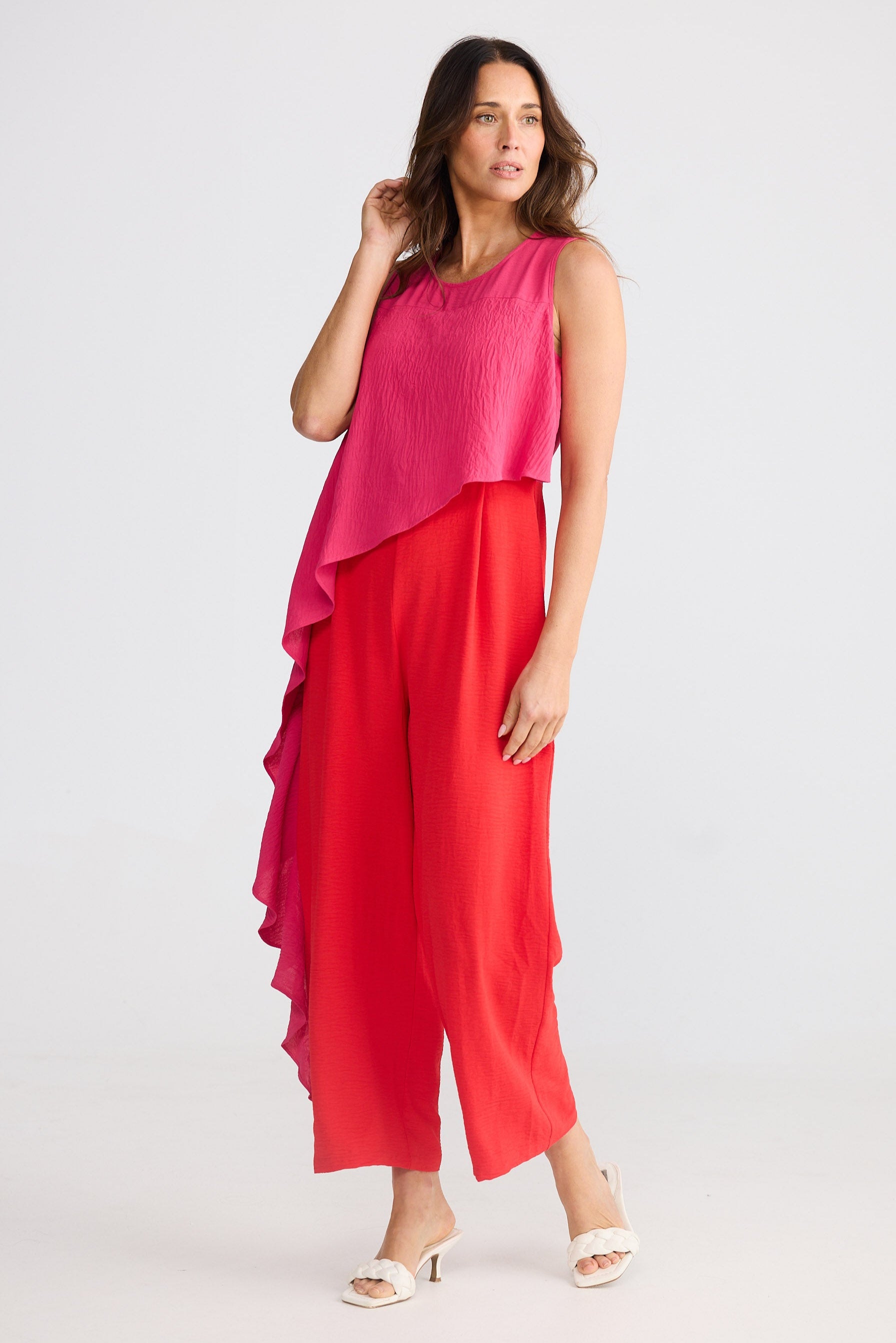 Woman wearing a pink and red pantsuit on a white background