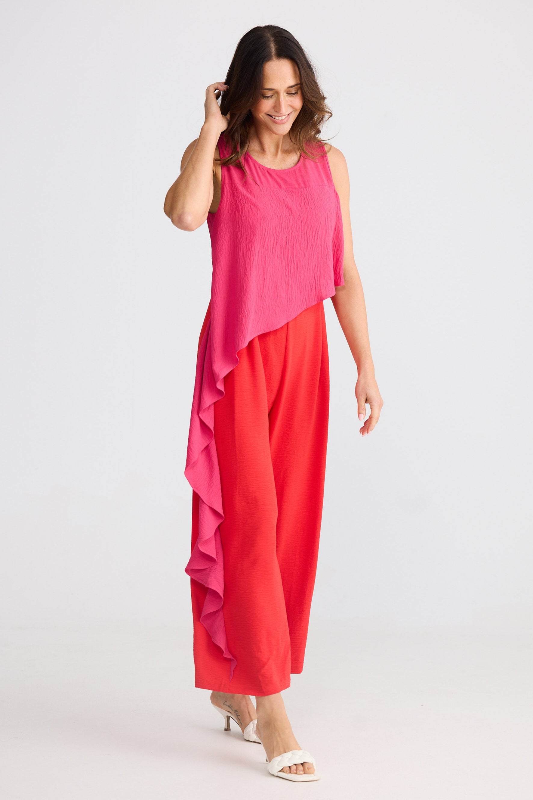 Woman wearing a pink and red pantsuit on a white background