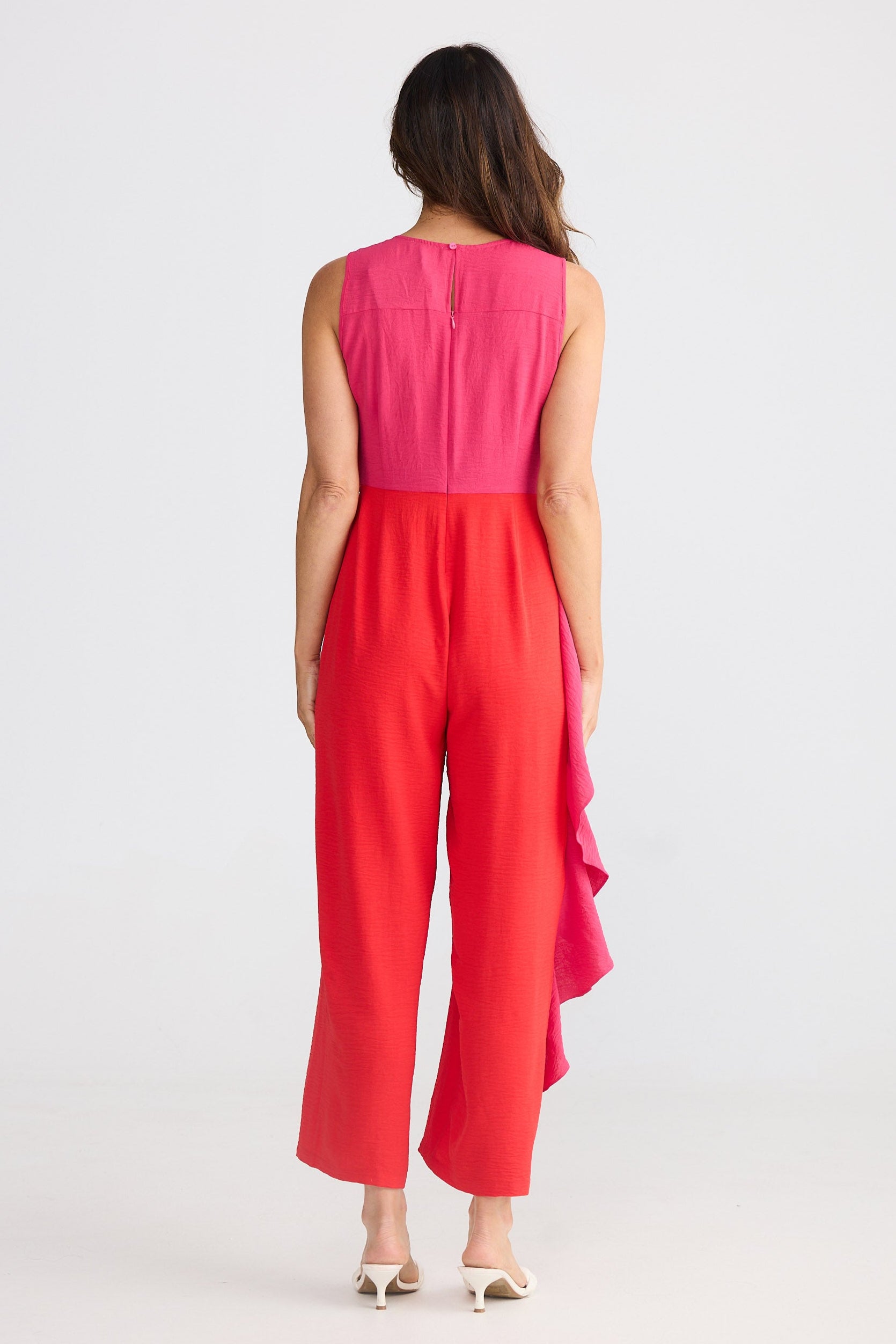 Woman wearing a pink and red pantsuit on a white background