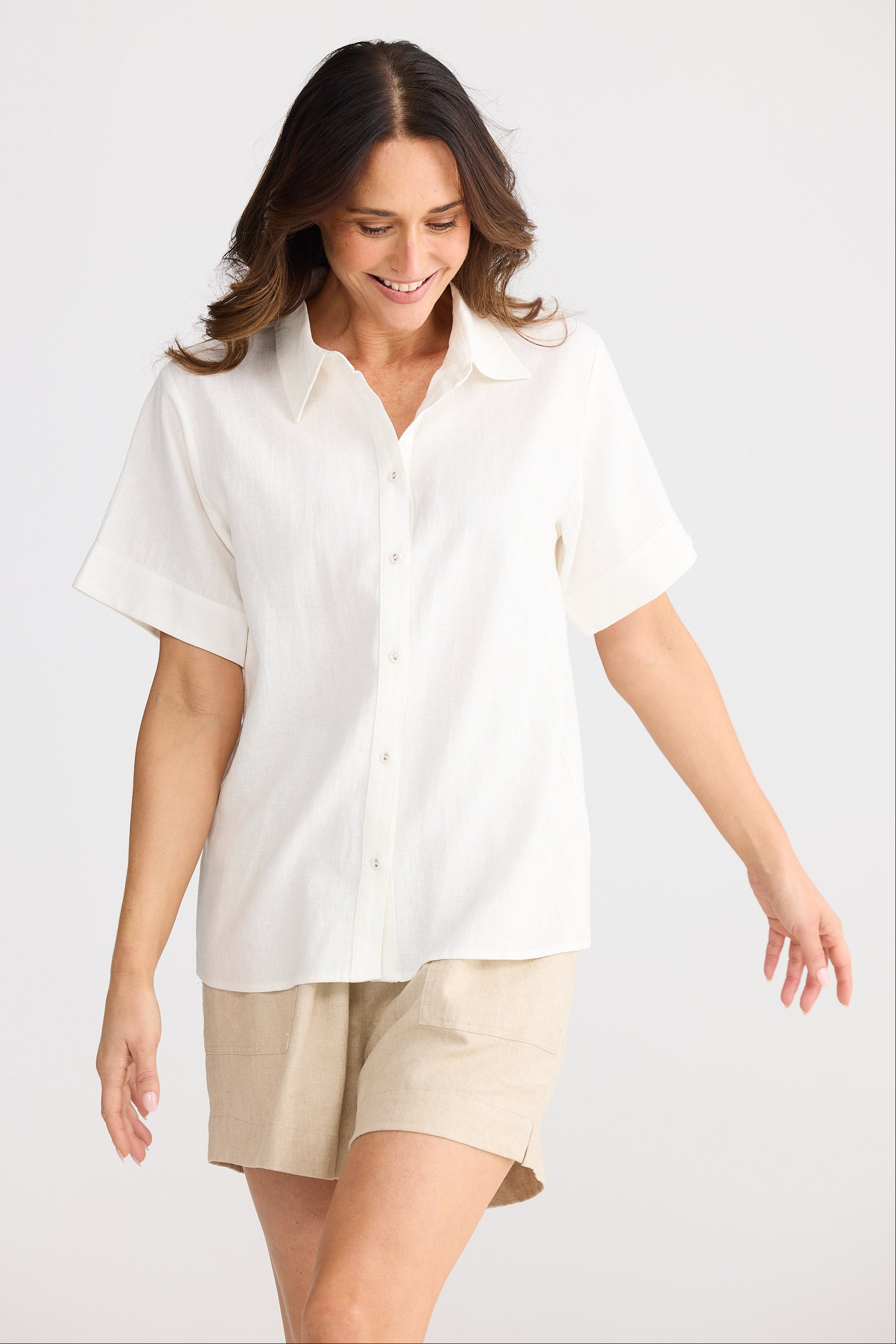 Woman wearing a white shirt and beige shorts on a white background