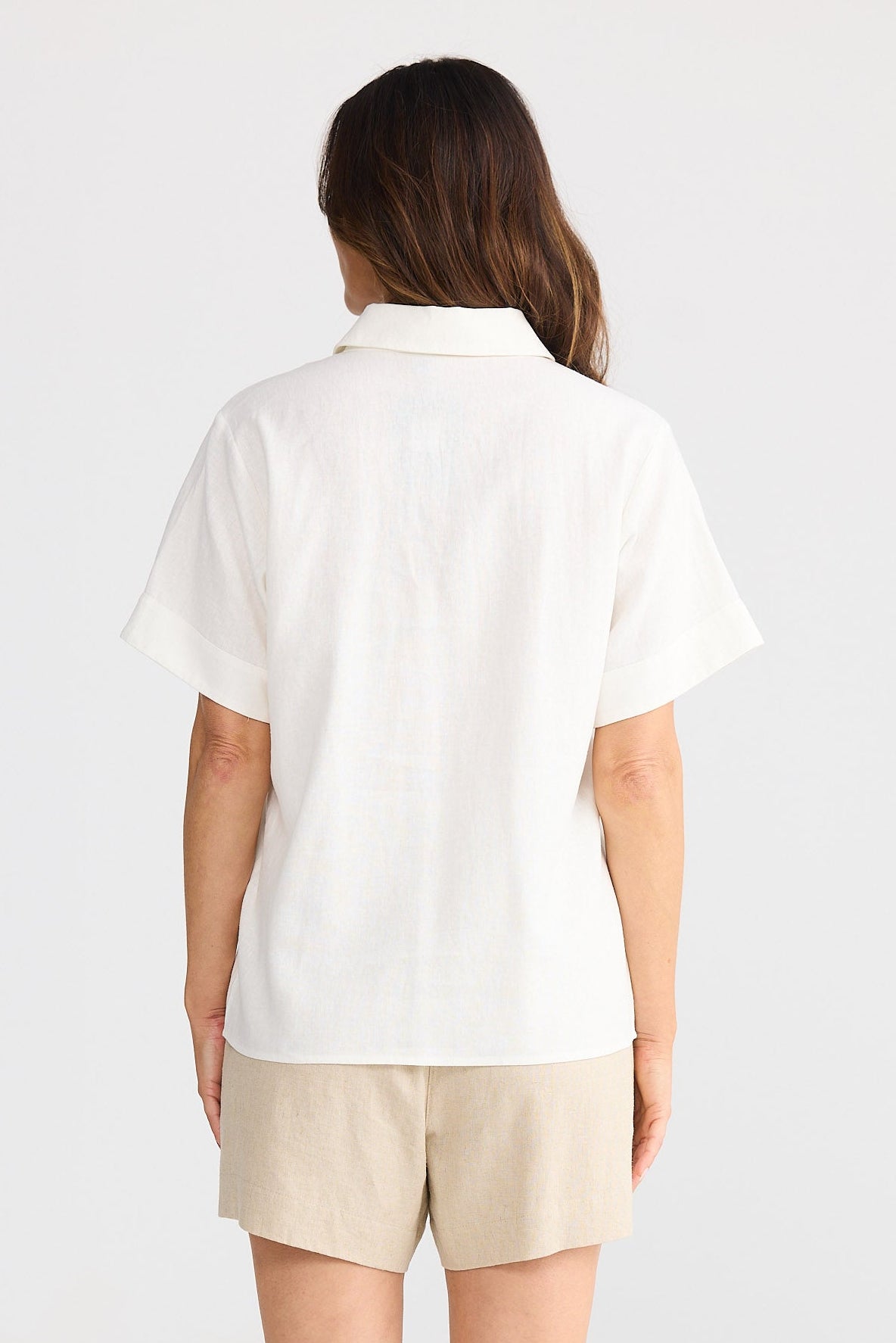 Person wearing a white shirt and beige shorts on a white background