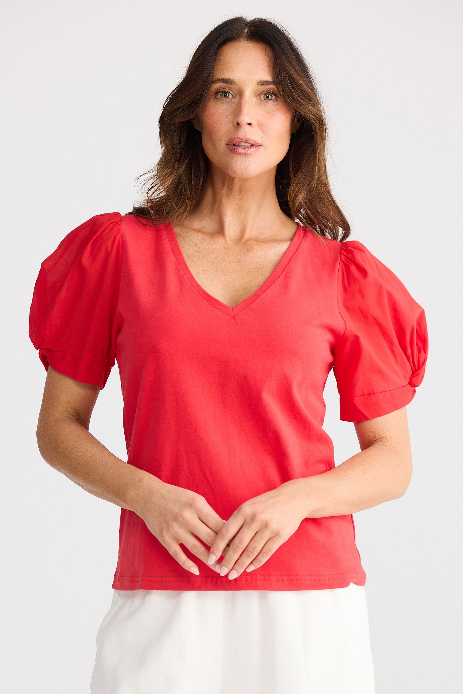 Woman wearing a red blouse with puff sleeves on a white background
