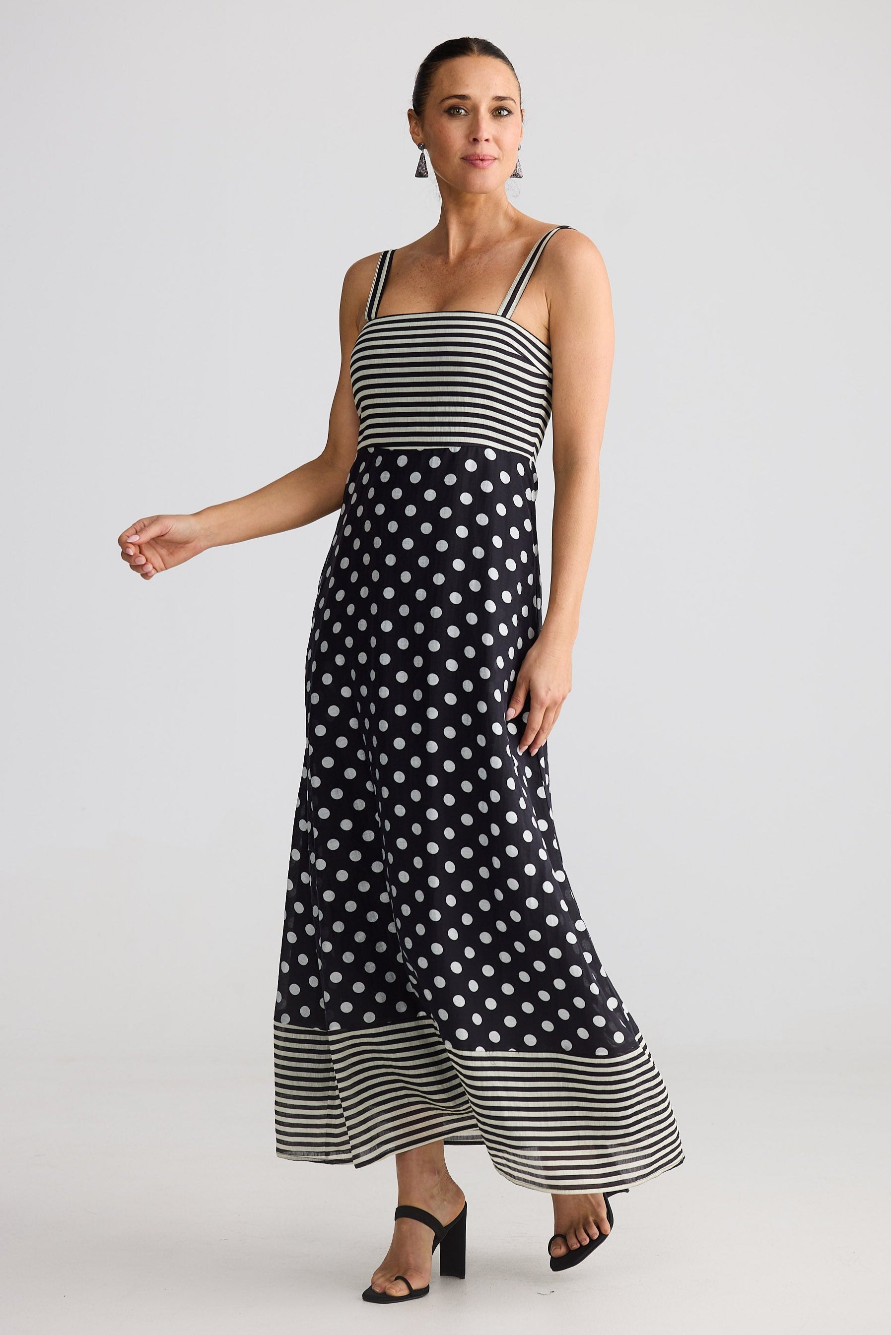 Woman wearing a black and white polka dot dress with a striped top on a white background