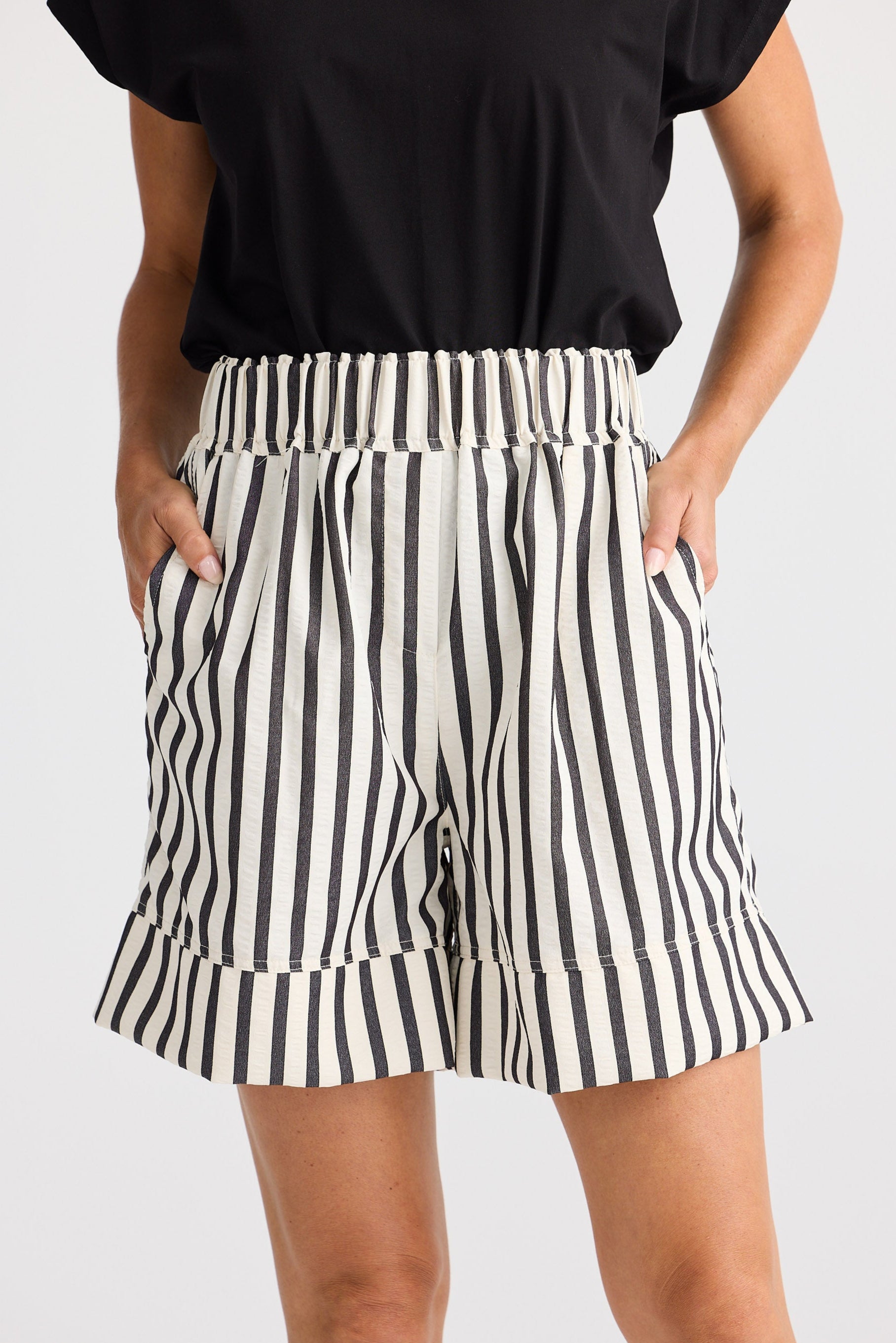Person wearing black and white striped shorts on a plain background