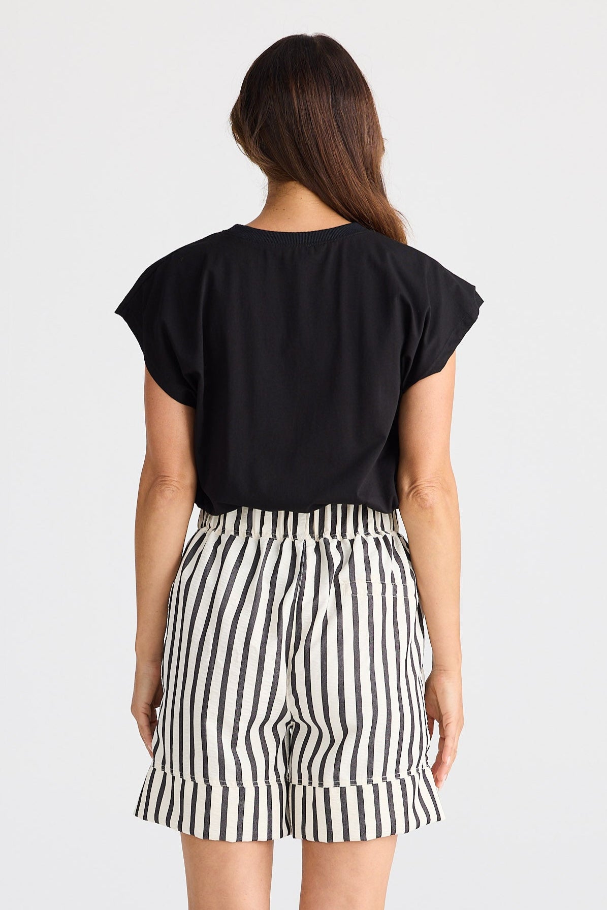 Person wearing a black top and striped shorts on a white background