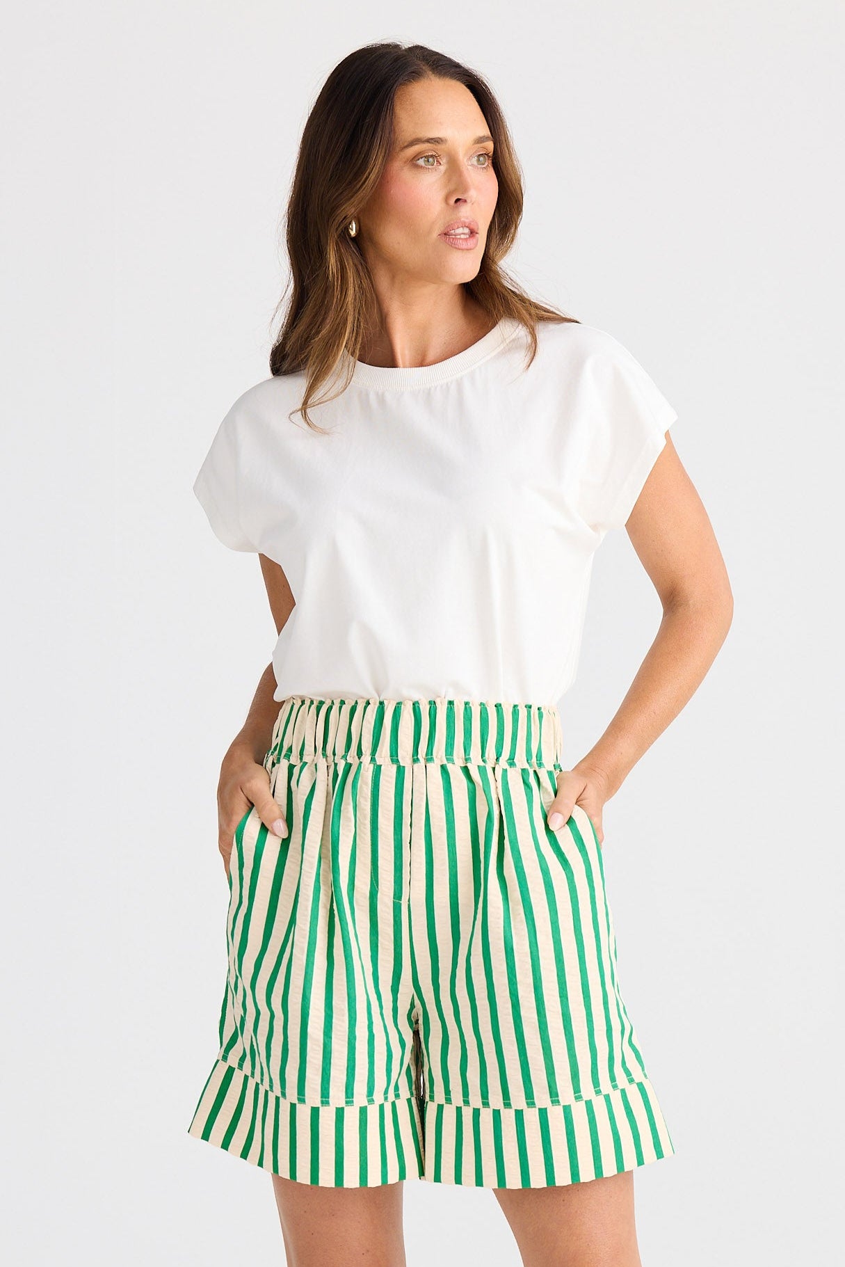 Woman wearing a white top and green striped shorts on a white background