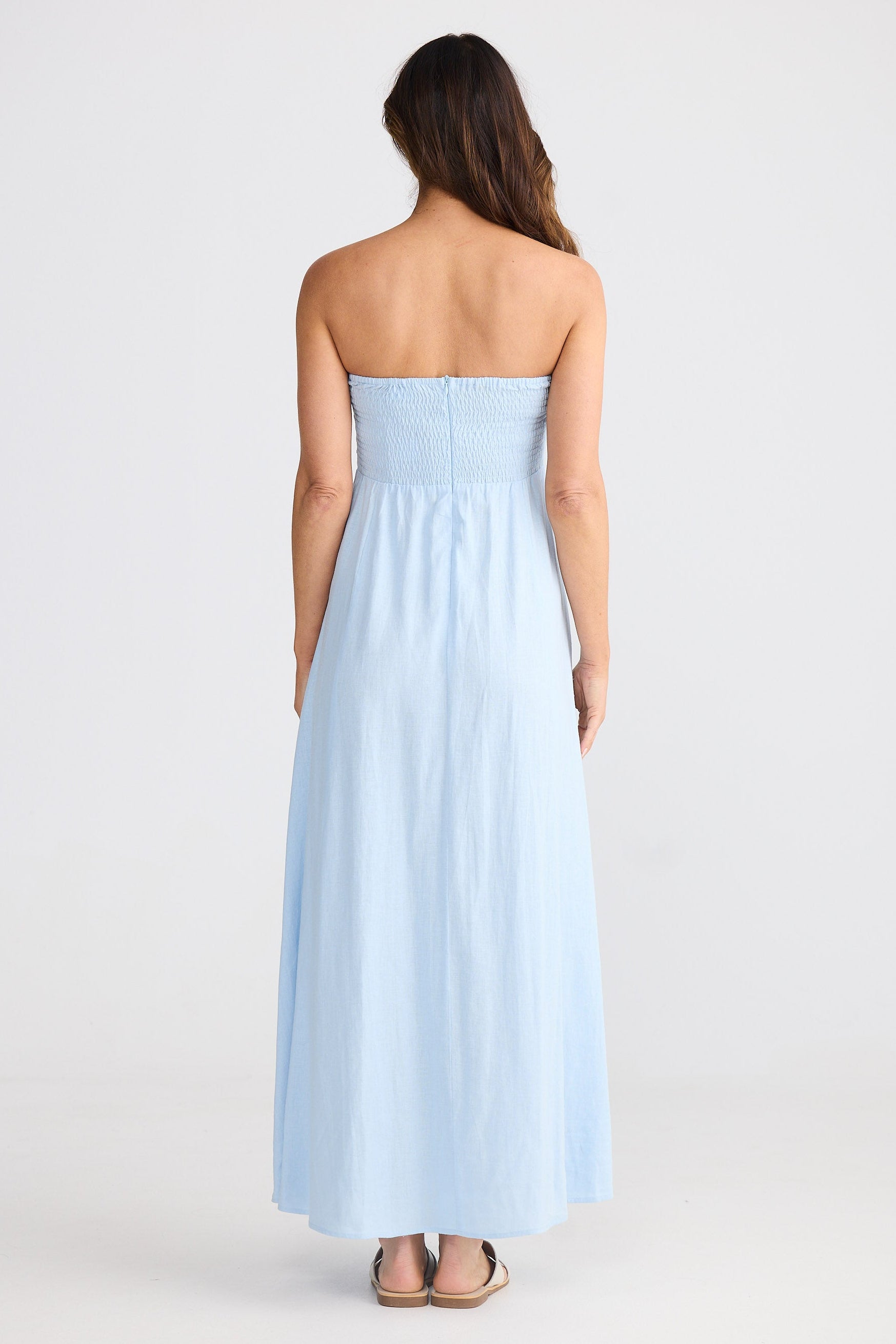 Woman wearing a light blue strapless dress on a white background