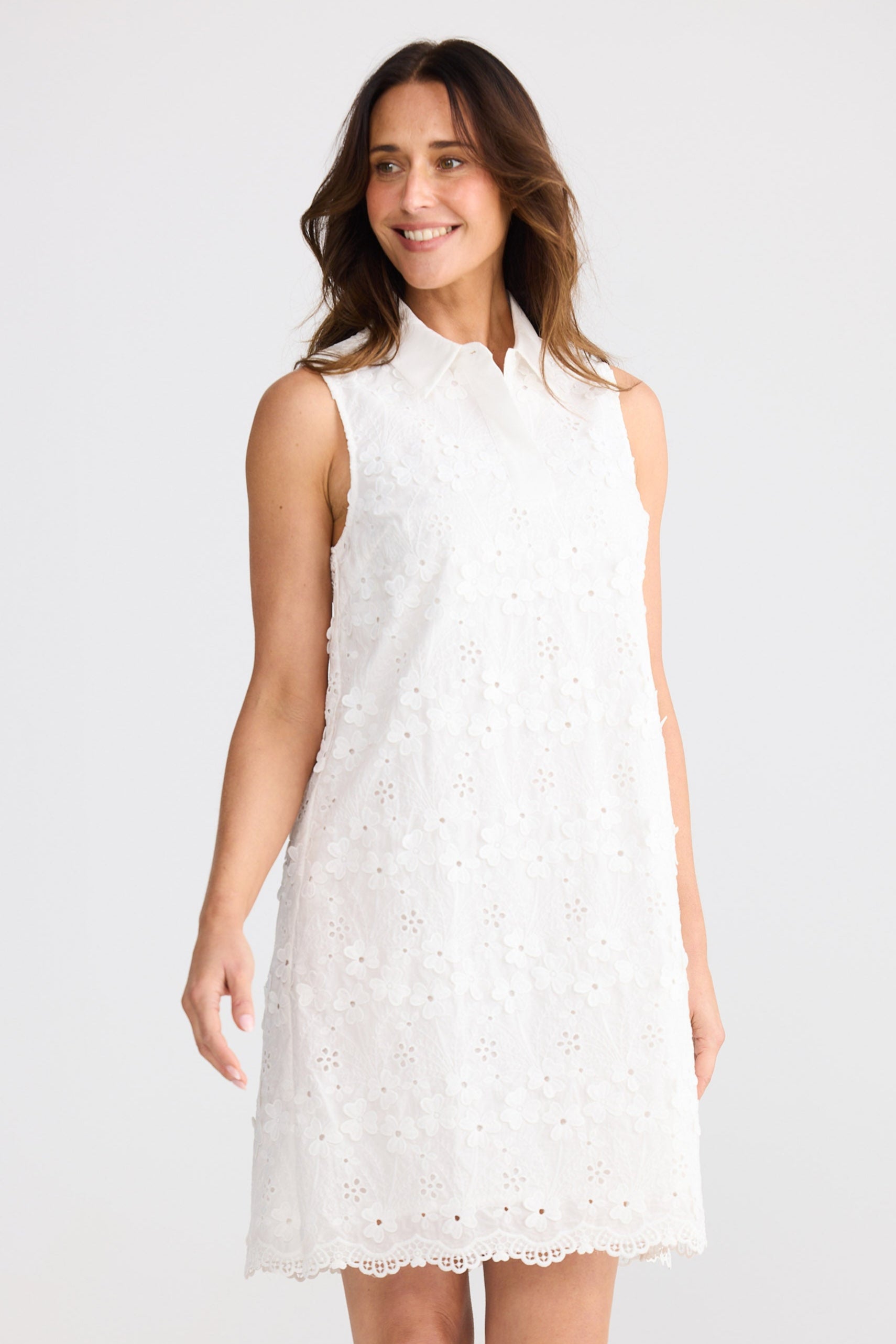 Woman wearing a white sleeveless dress against a plain background