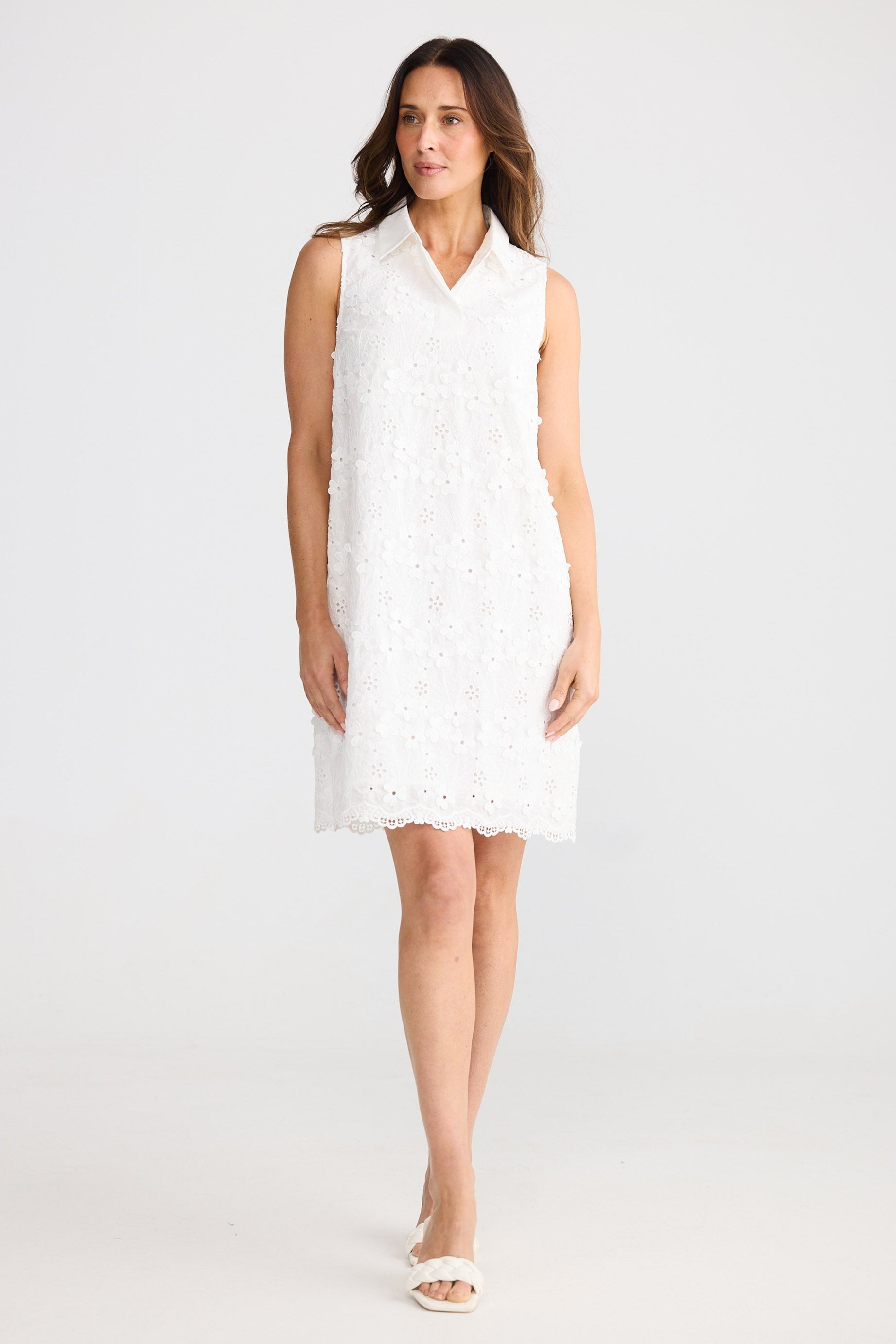 Woman wearing a white sleeveless dress against a plain background