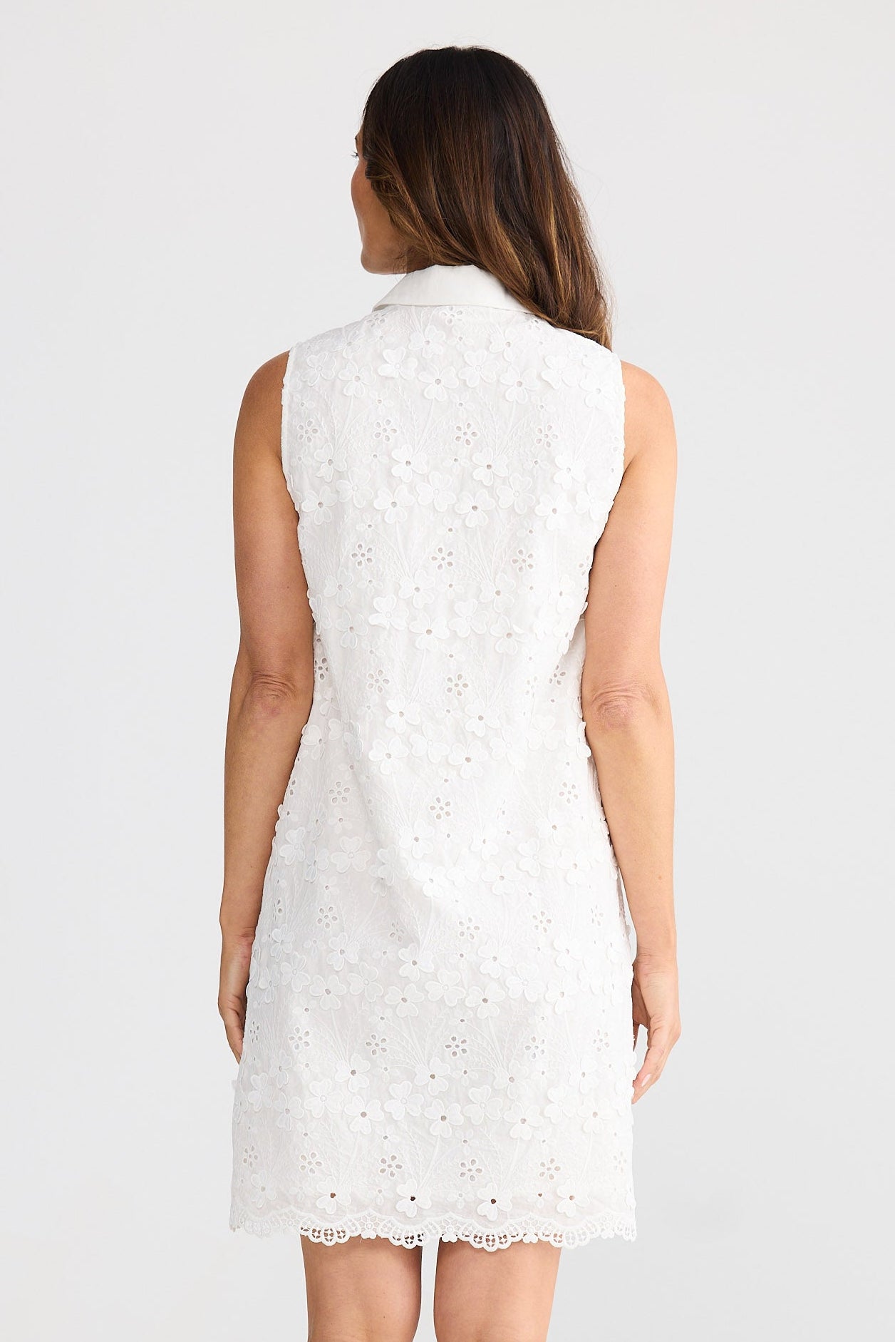 Woman wearing a white lace dress on a plain background