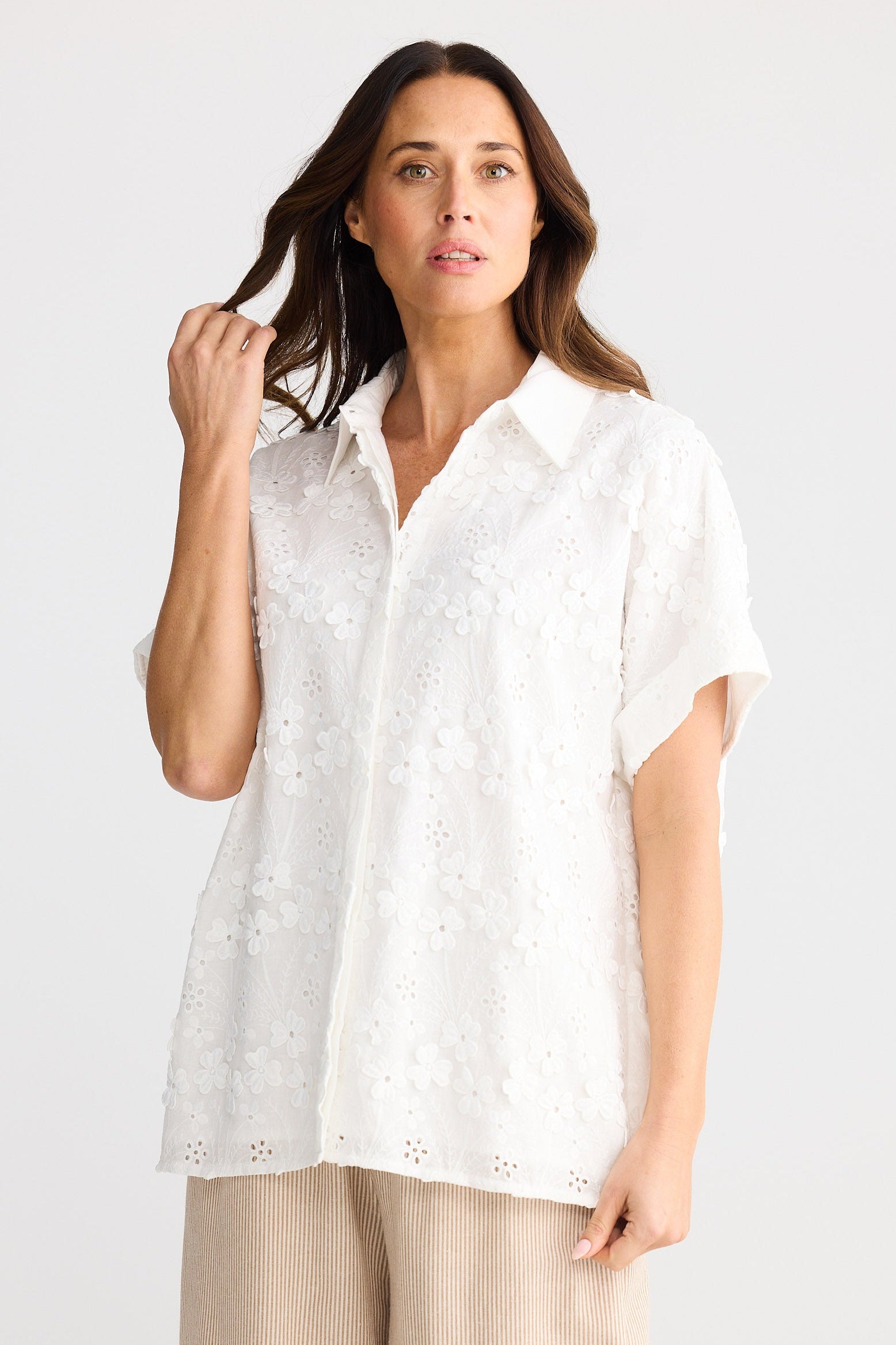 Woman wearing a white blouse with short sleeves on a plain background