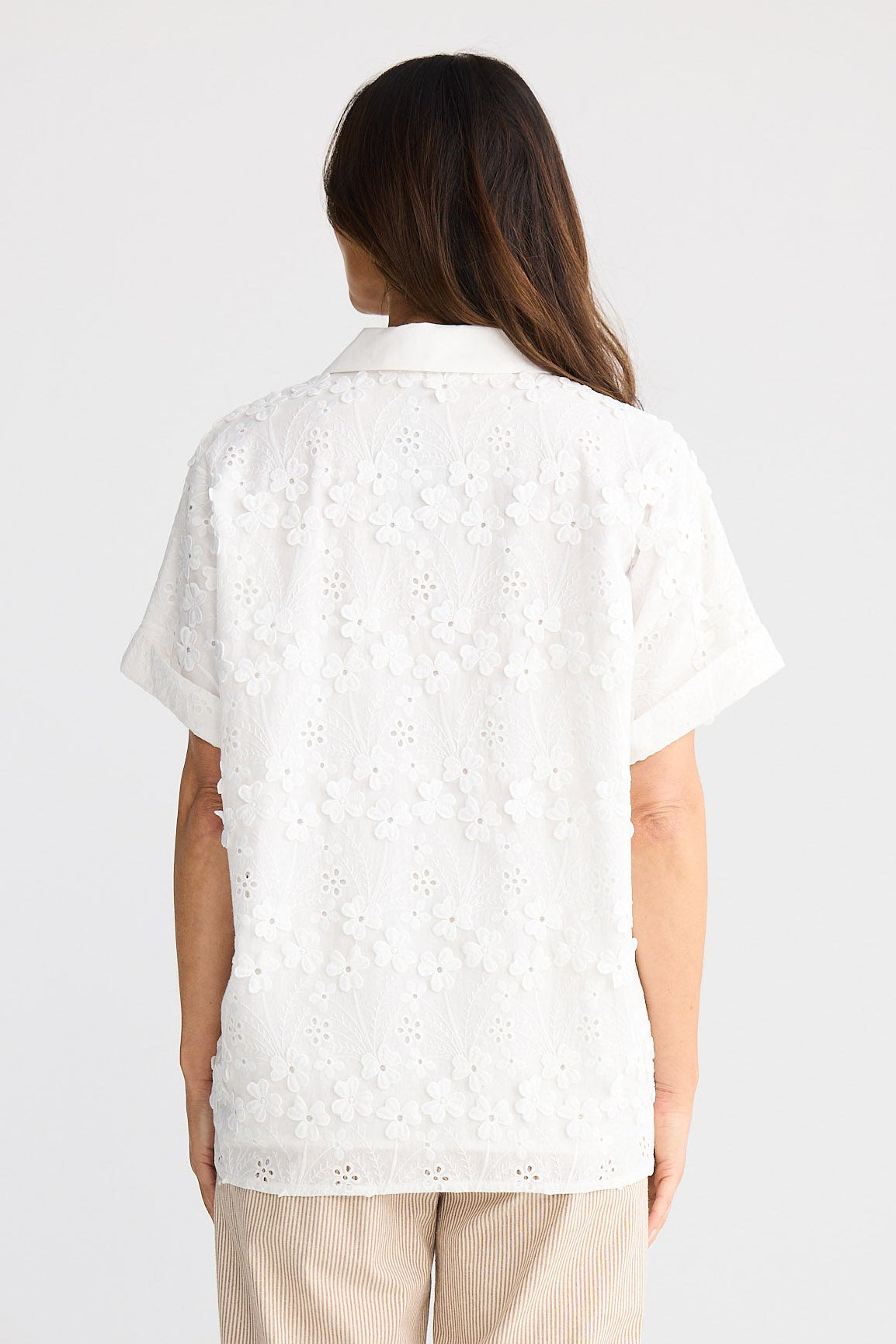 Woman wearing a white blouse and beige pants on a white background