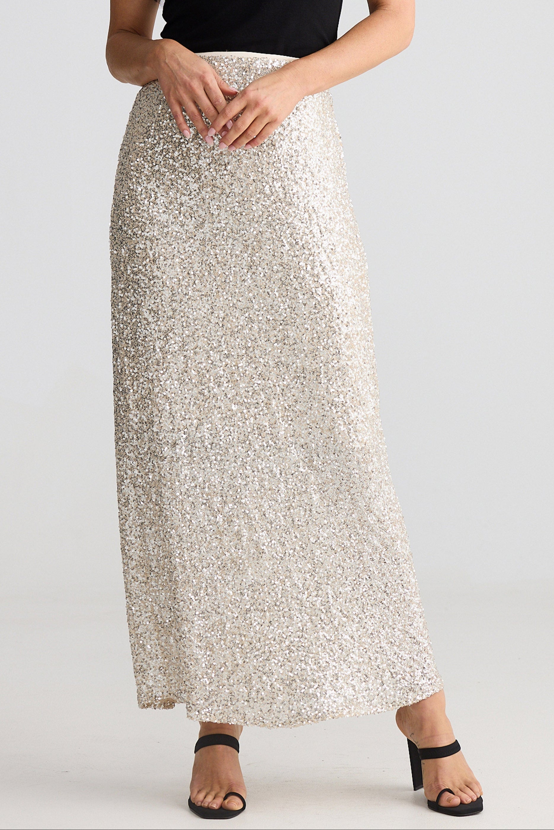 Person wearing a silver sequin skirt on a plain background