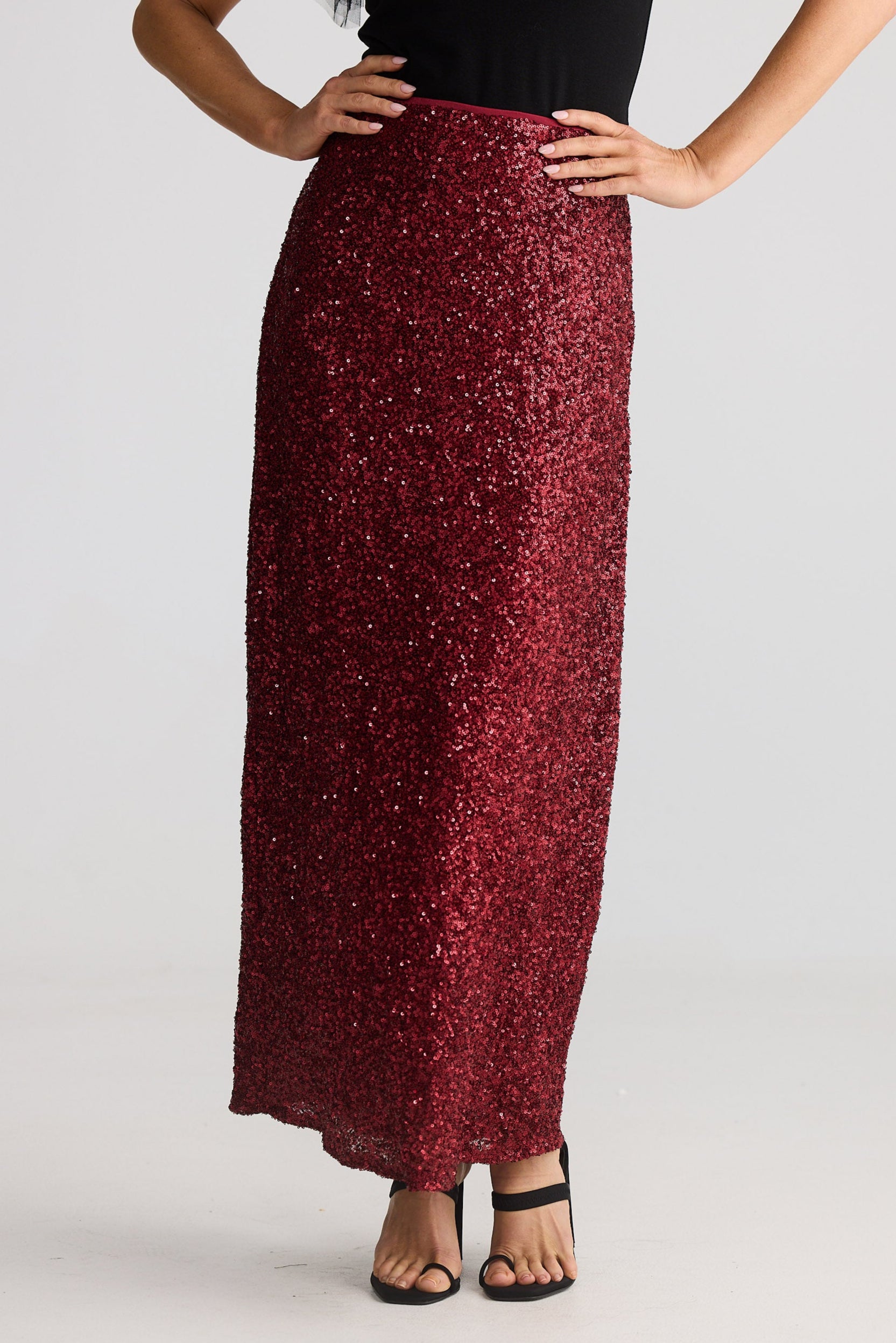 Person wearing a burgundy sequin skirt on a plain background