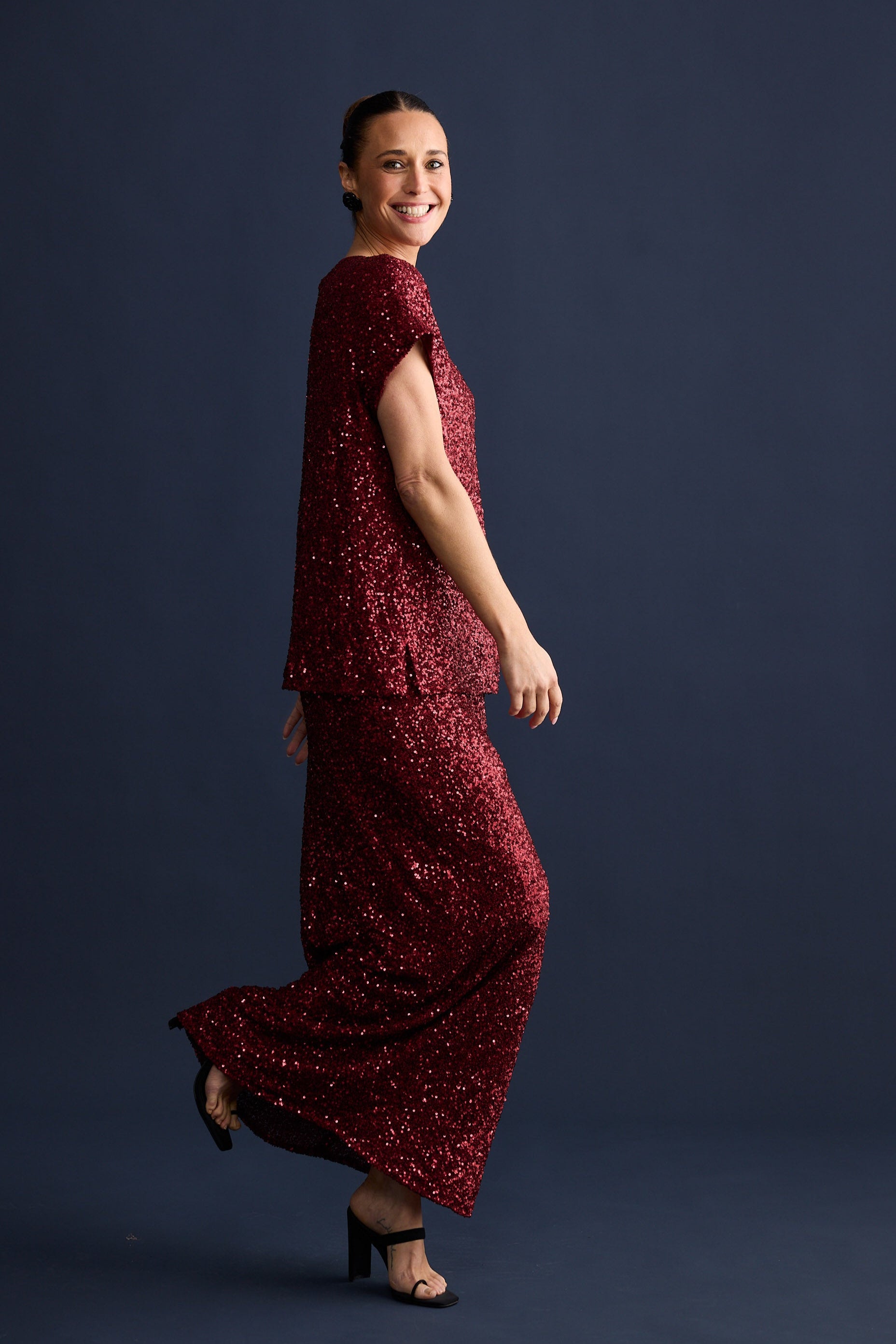 Woman wearing a red sequin skirt and top against a dark background