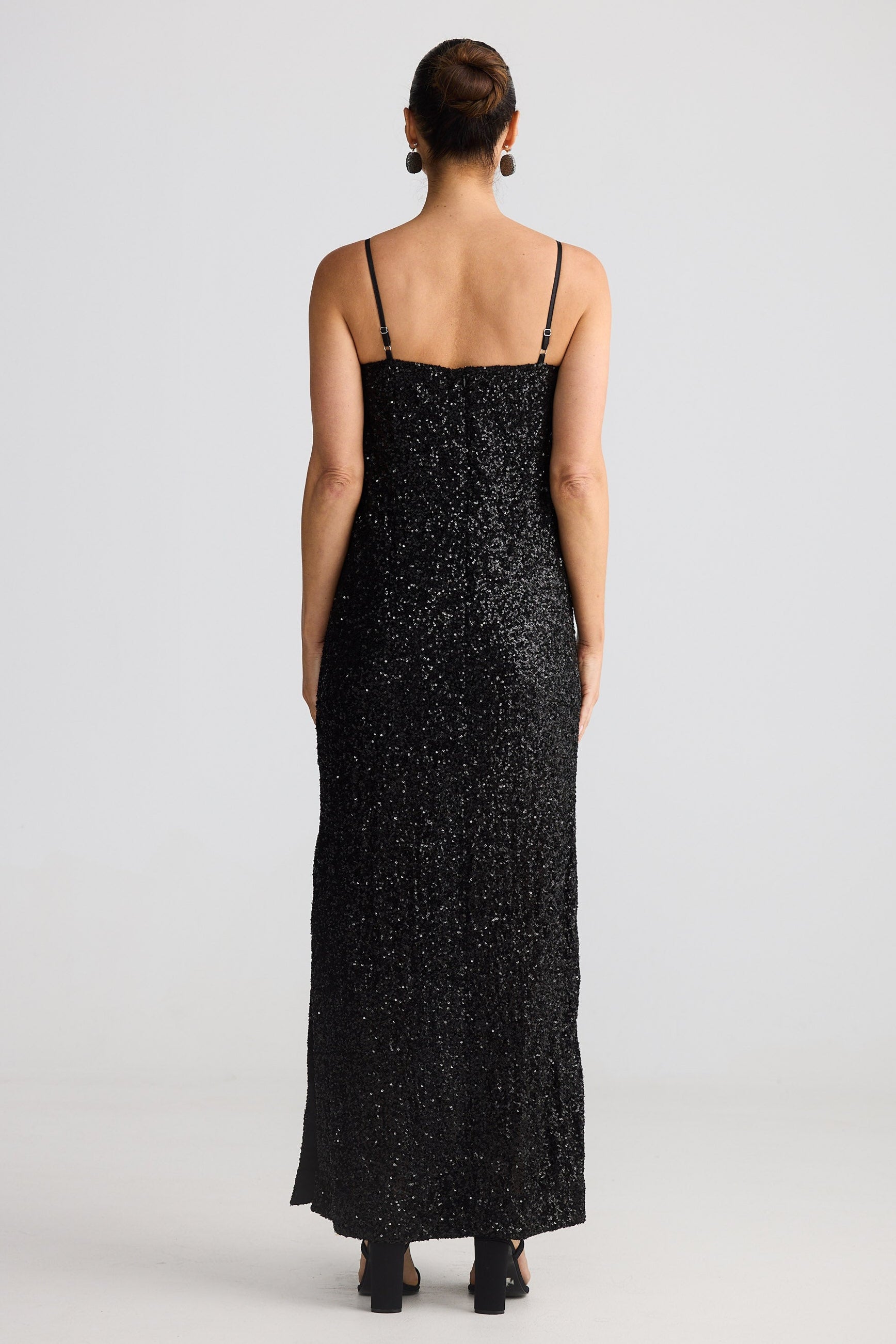 Woman wearing a black sequin dress from behind on a white background