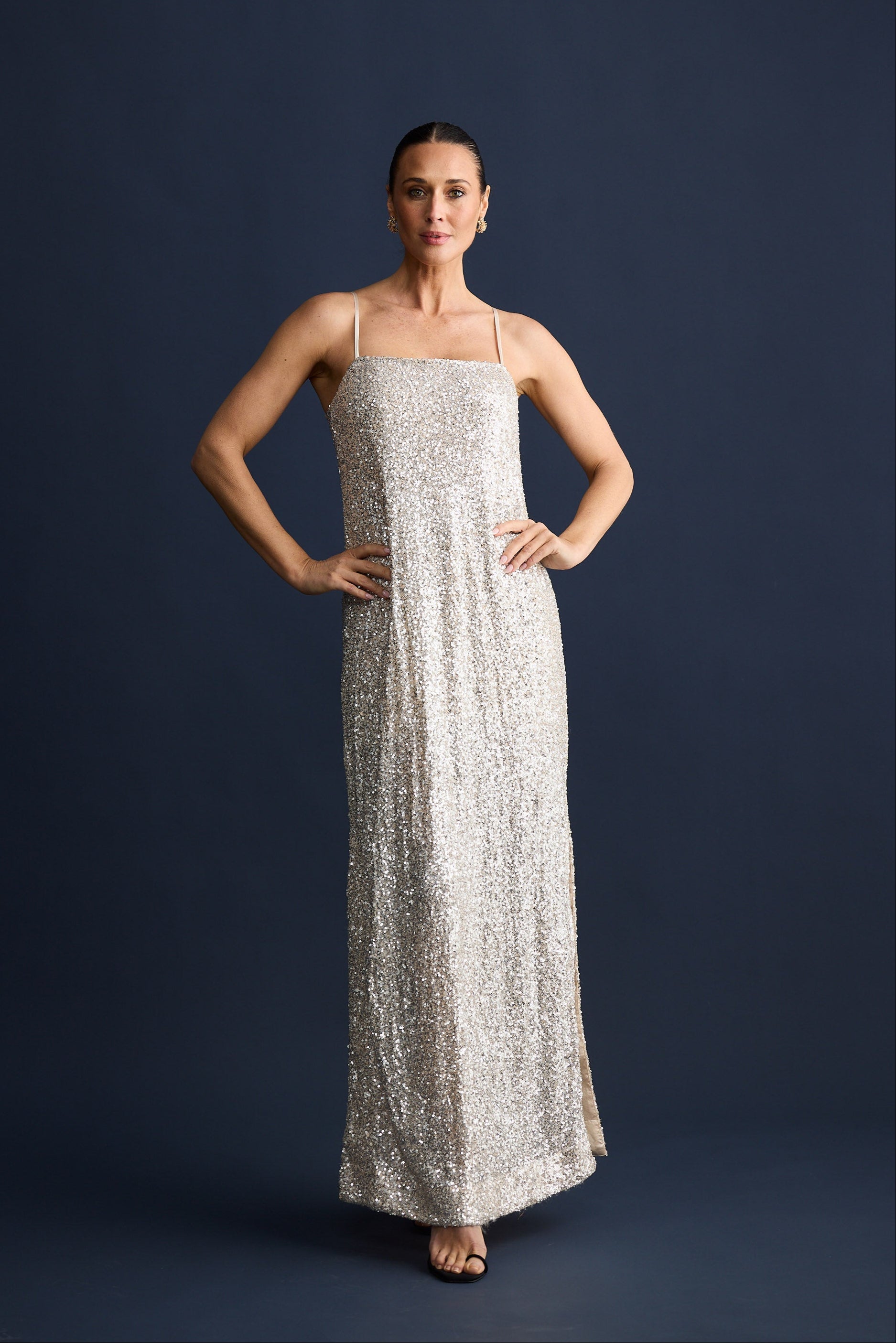 Woman wearing a silver sequin dress against a dark blue background
