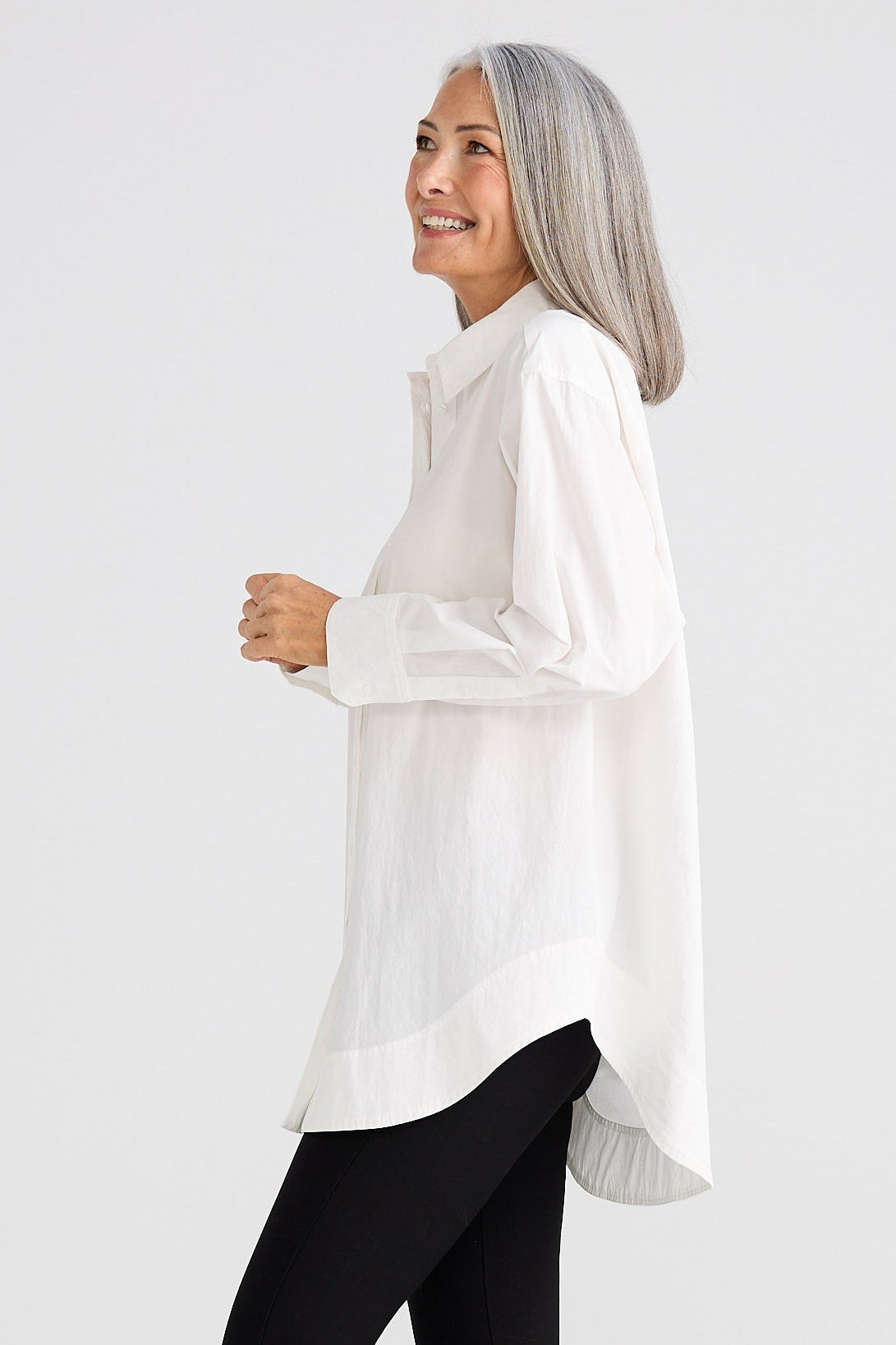 Woman wearing a white blouse and black leggings on a white background