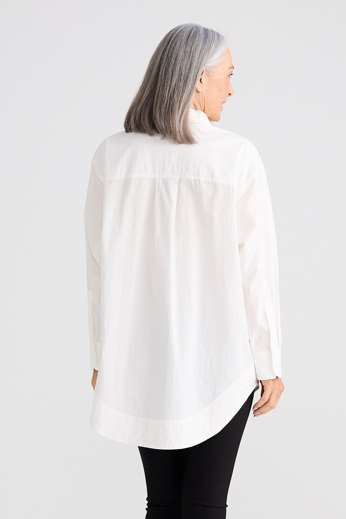 Person wearing a white blouse and black pants on a white background