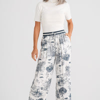Woman wearing a white top and floral pants on a white background