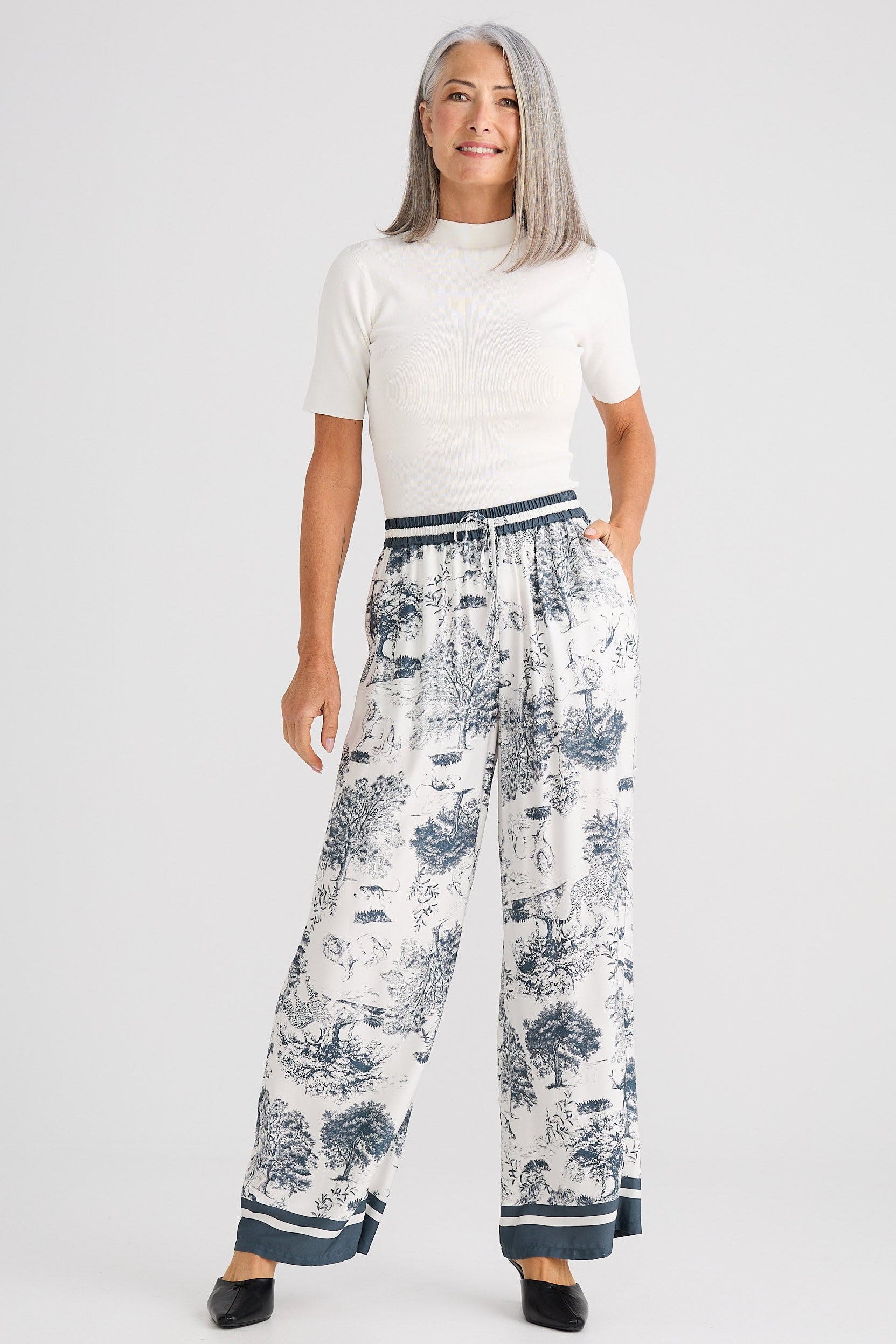 Woman wearing a white top and floral pants on a white background