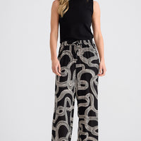Woman wearing a black sleeveless top and patterned pants on a white background