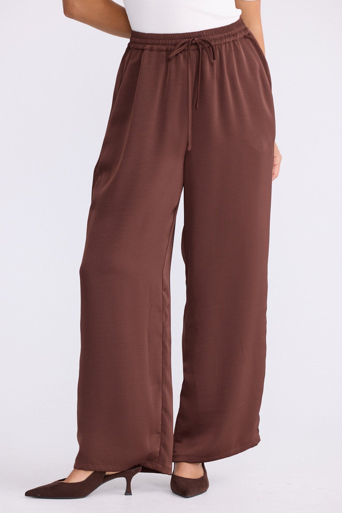 Model wearing Glenda Pant brown pants with adjustable drawstring waist, straight-leg fit, front view on white background