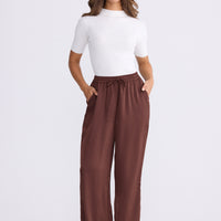 Model wearing Glenda Pant brown pants, straight-leg fit, alternate studio view on white background