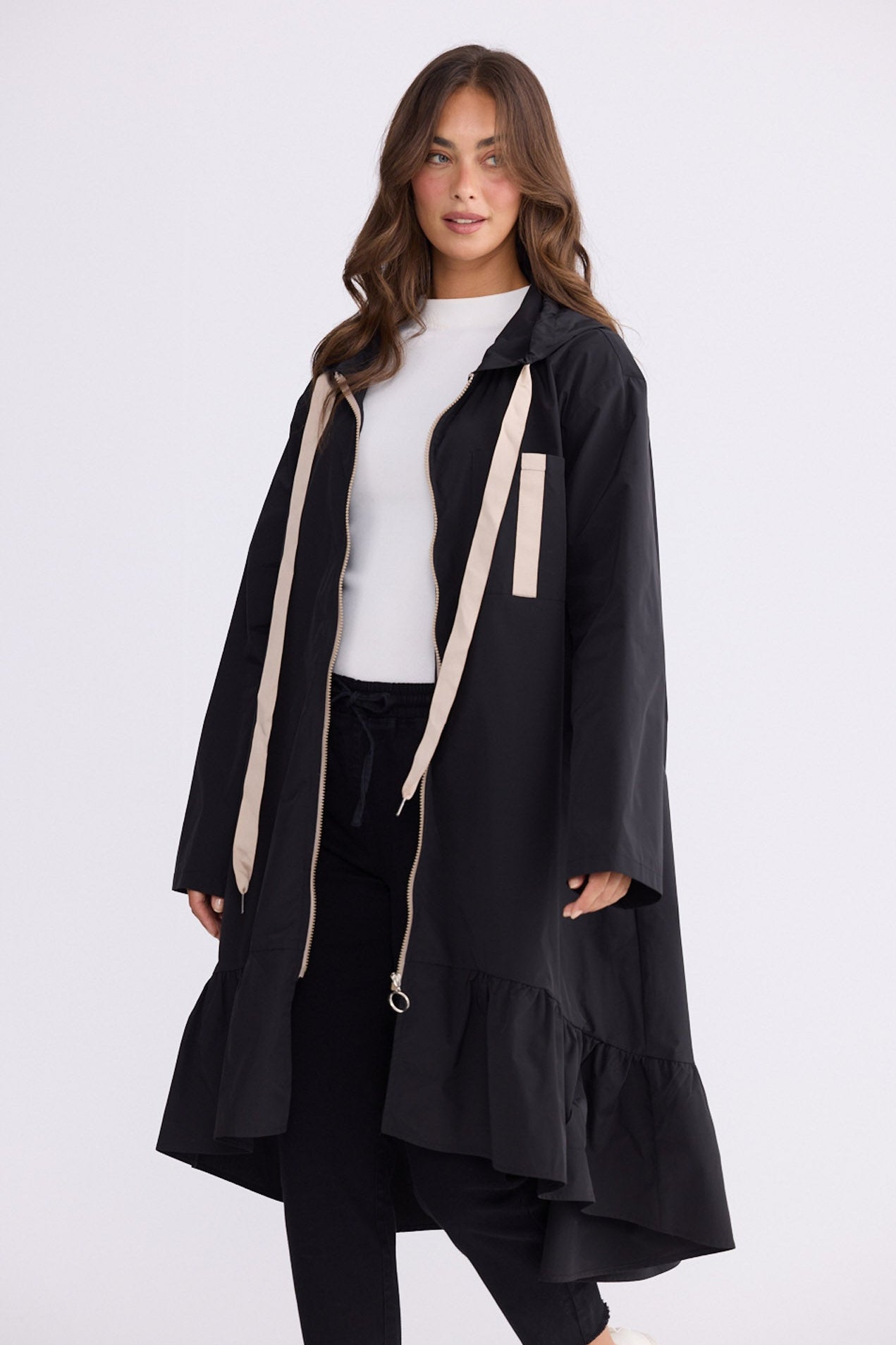 Model wearing Hyacinth Raincoat in black with hood and long sleeves, front view on white background
