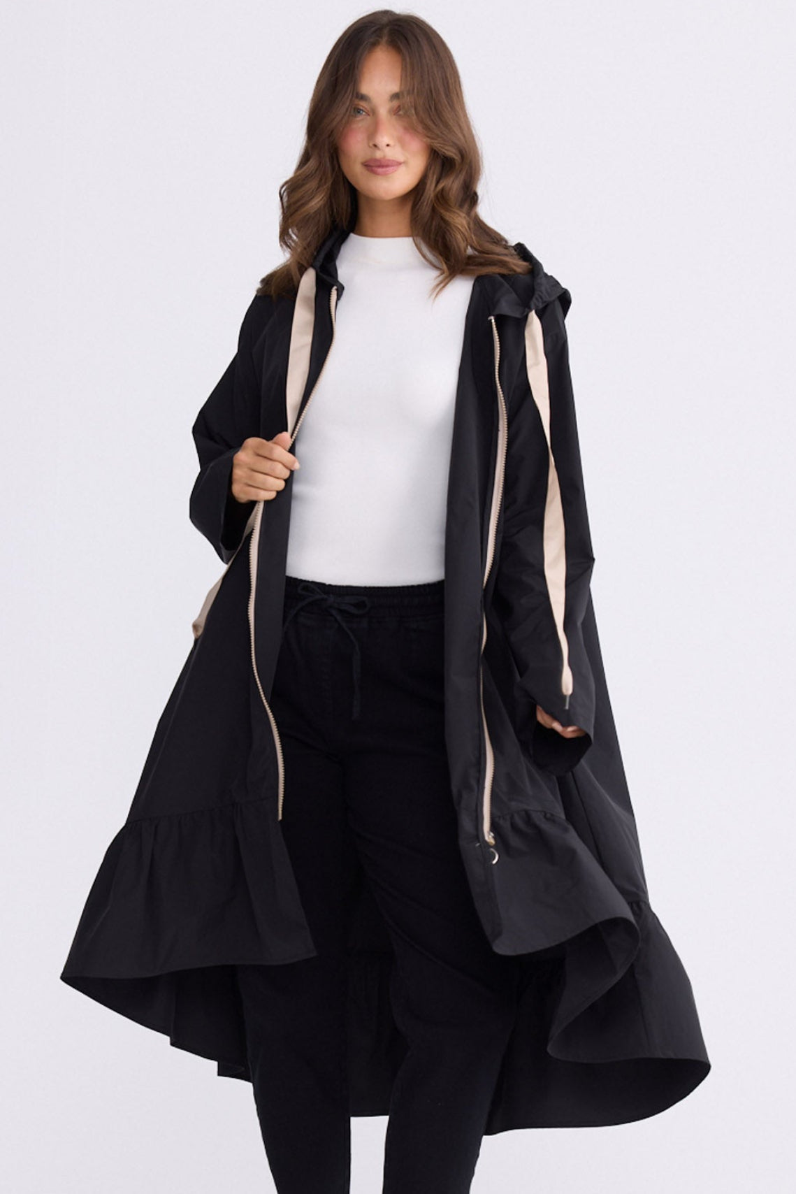 Model wearing Hyacinth Raincoat in black with hood and long sleeves, front view on white background