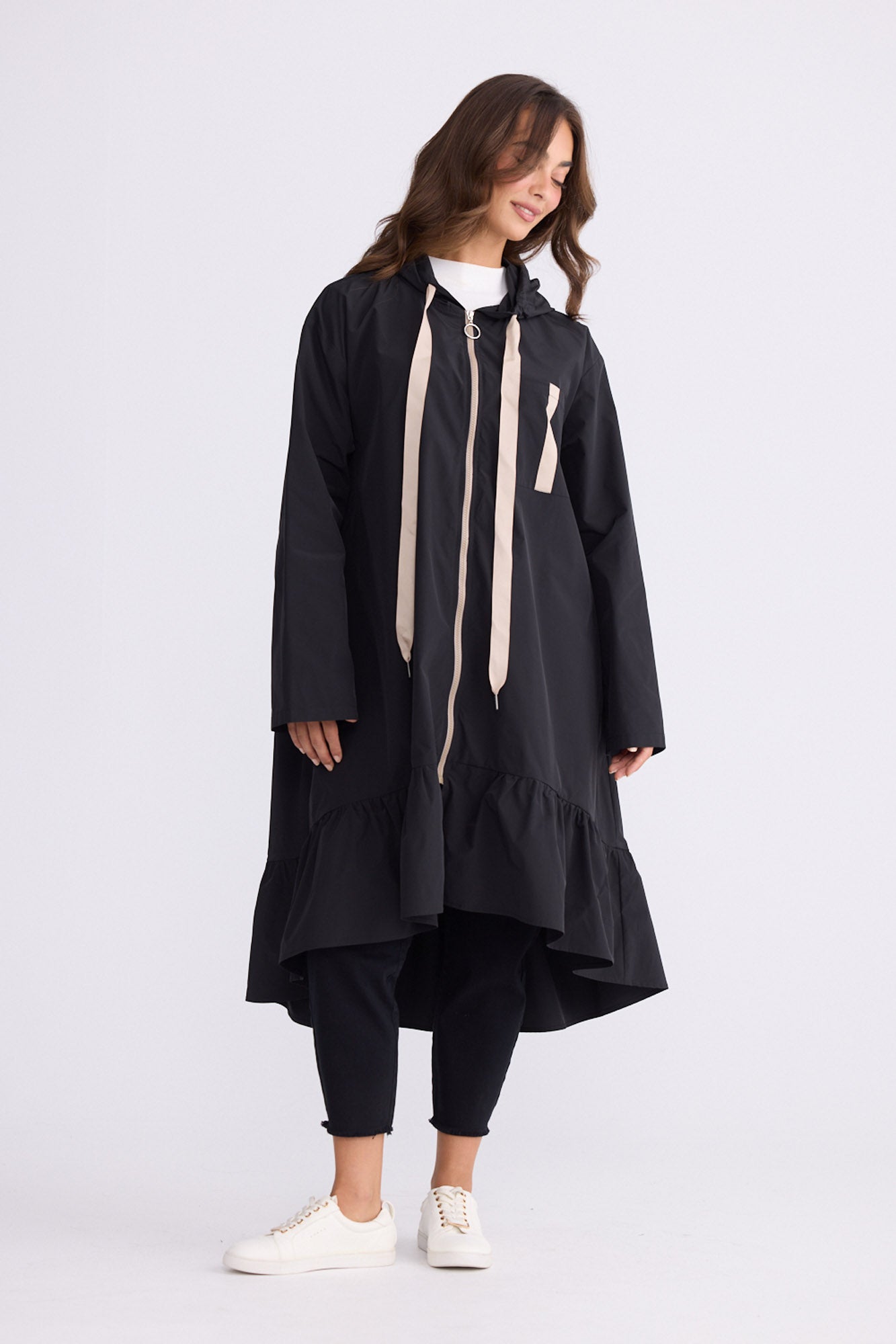 Model wearing Hyacinth Raincoat in black with hood and long sleeves, front view on white background