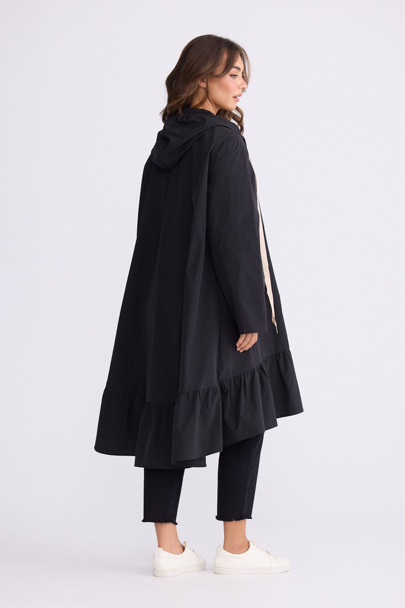 Model wearing Hyacinth Raincoat in black with hood and long sleeves, back view on white background