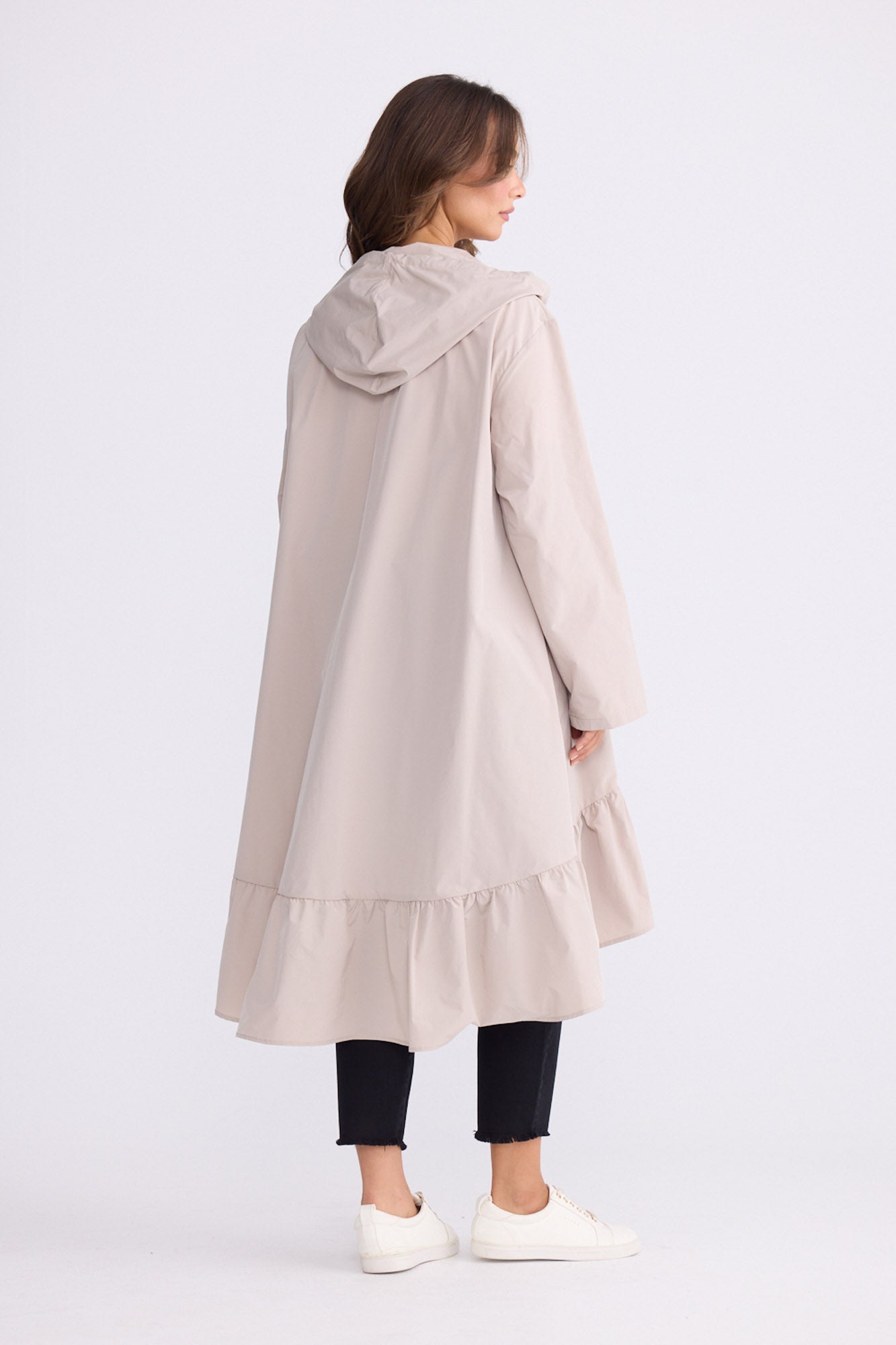 Model wearing Hyacinth Raincoat in beige with hood and long sleeves, detail view on white background
