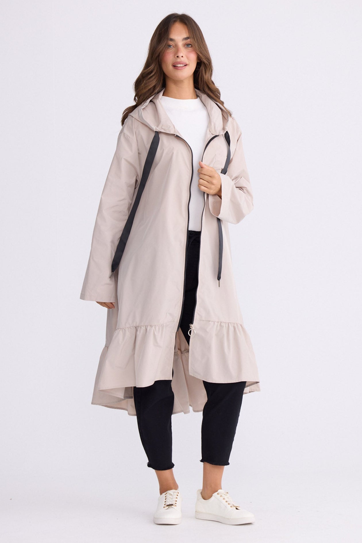 Model wearing Hyacinth Raincoat in beige with hood and long sleeves, back view on white background