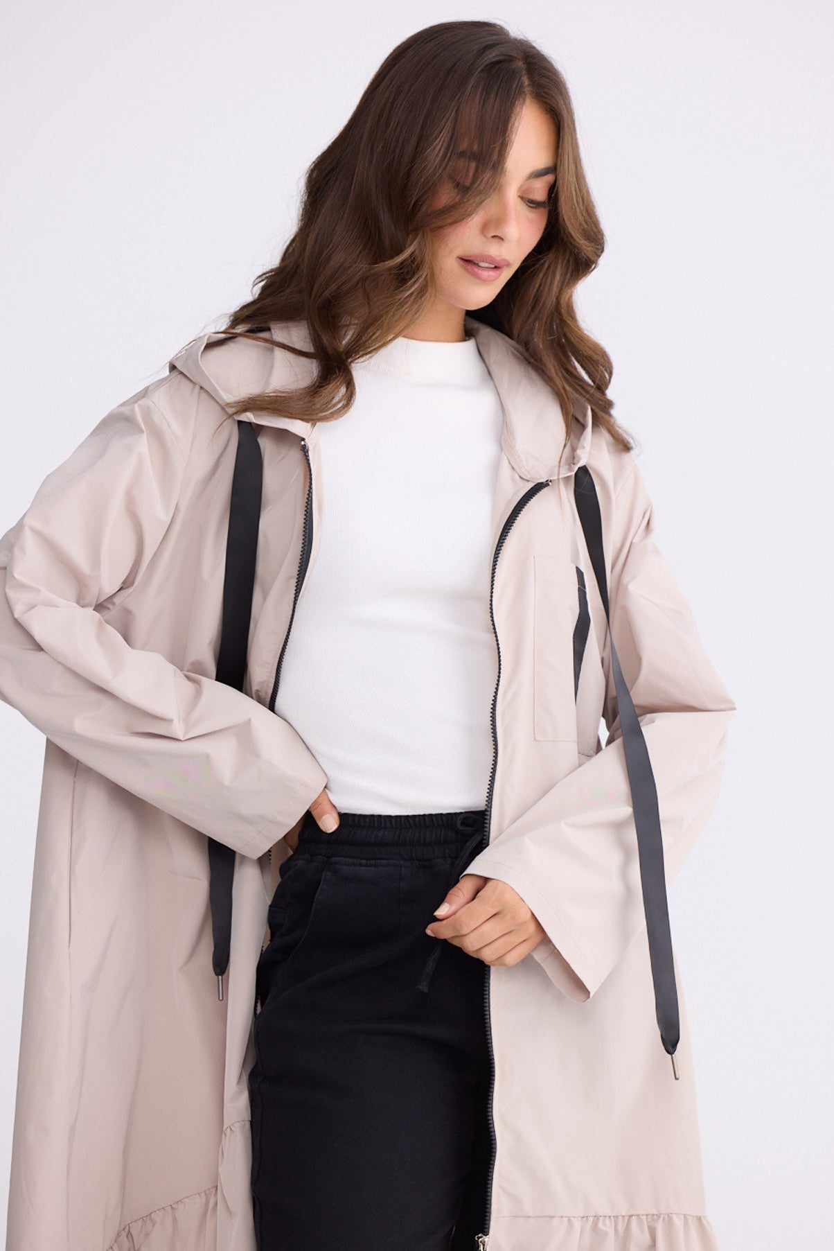 Model wearing Hyacinth Raincoat in beige with hood and long sleeves, front view on white background