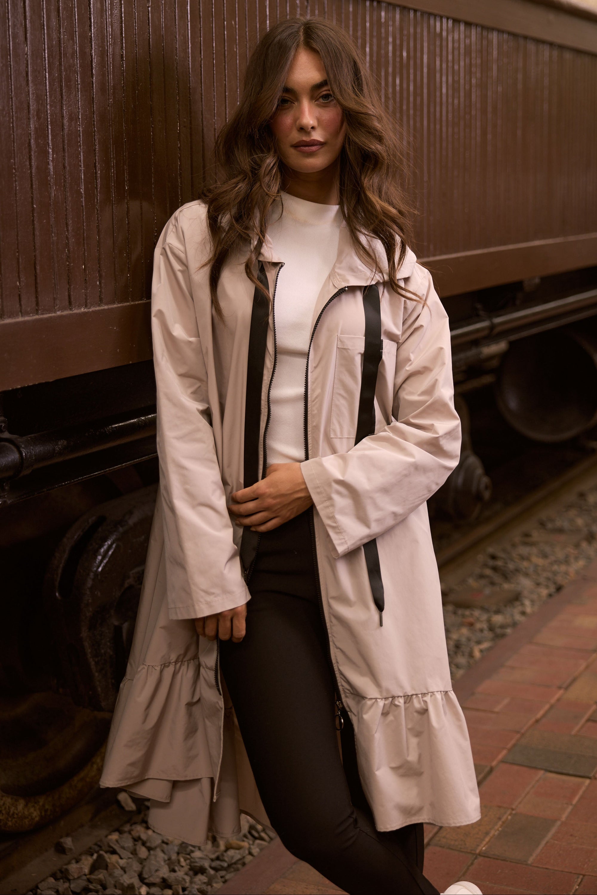 Model wearing Hyacinth Raincoat in beige with hood and long sleeves, detail view on white background