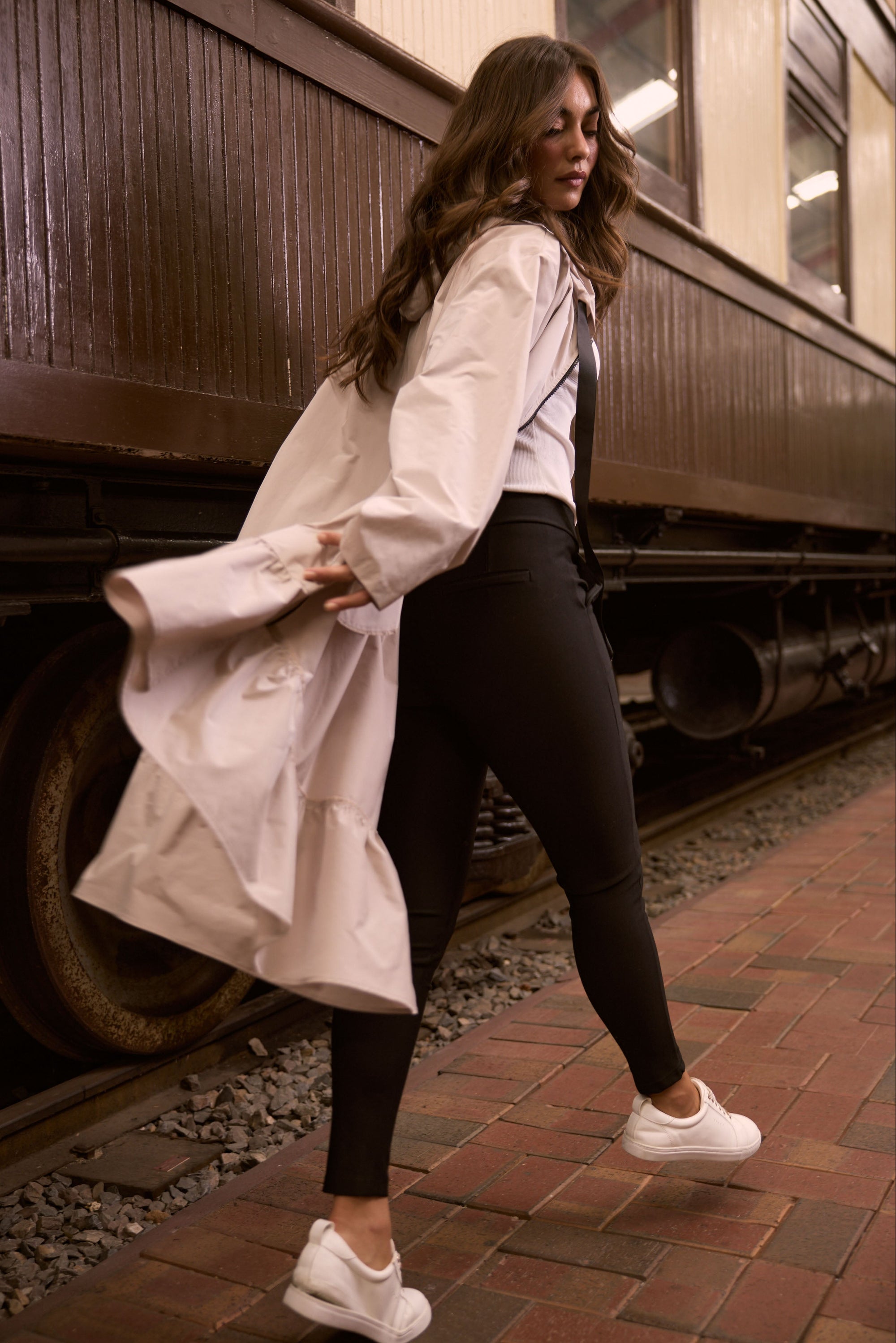 Model wearing Hyacinth Raincoat in beige with hood and long sleeves, detail view on white background