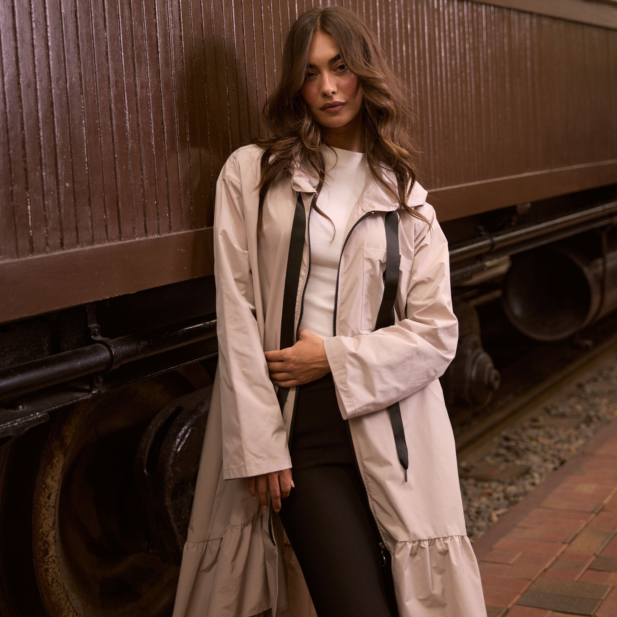 Woman in a white coat standing next to an old train