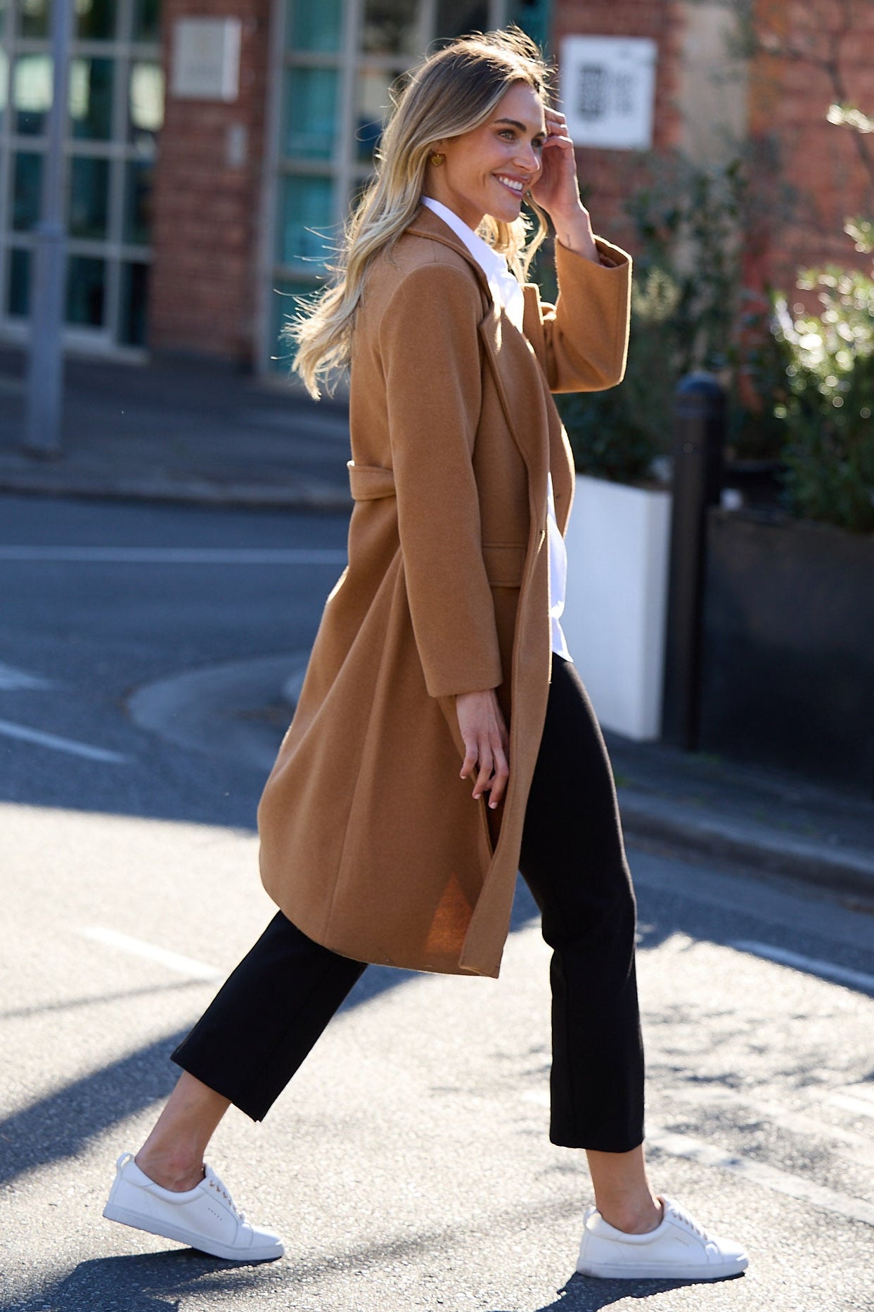 Woman in a brown coat walking on a street