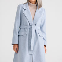 Woman wearing a light blue coat on a white background