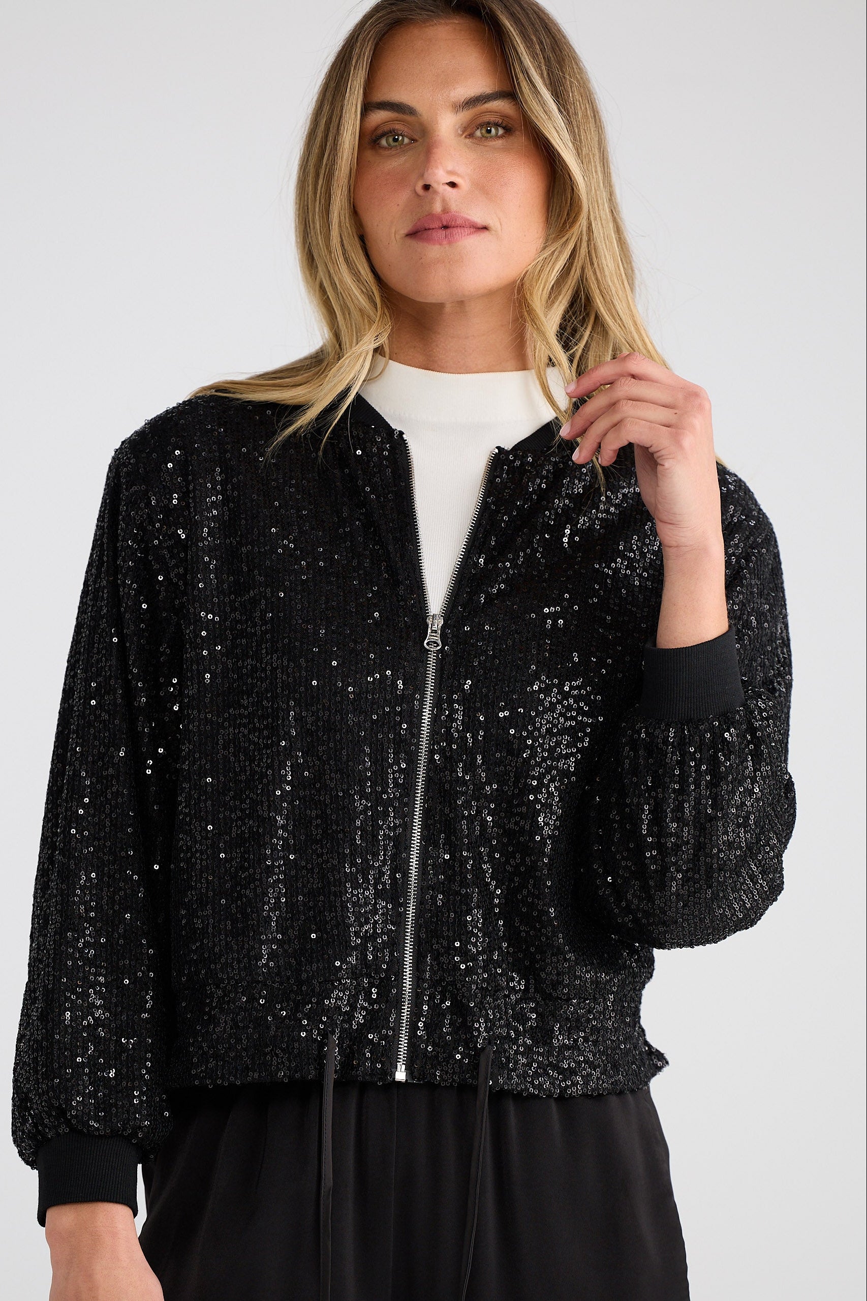 Woman wearing a black sequin jacket on a white background