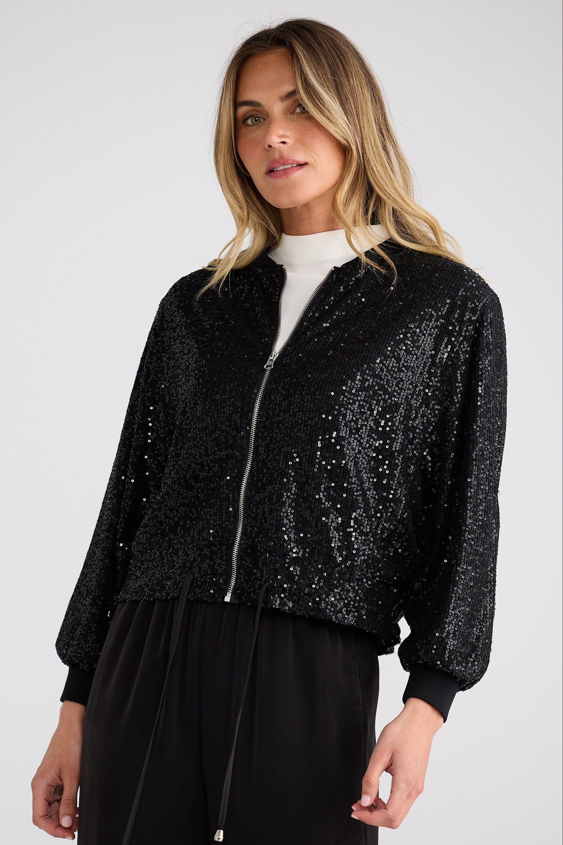 Woman wearing a black sequin jacket on a white background