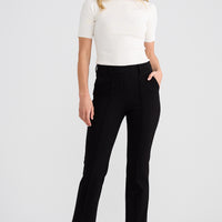 Woman wearing a white top and black pants on a white background