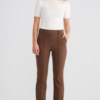 Woman wearing a white top and brown pants on a white background