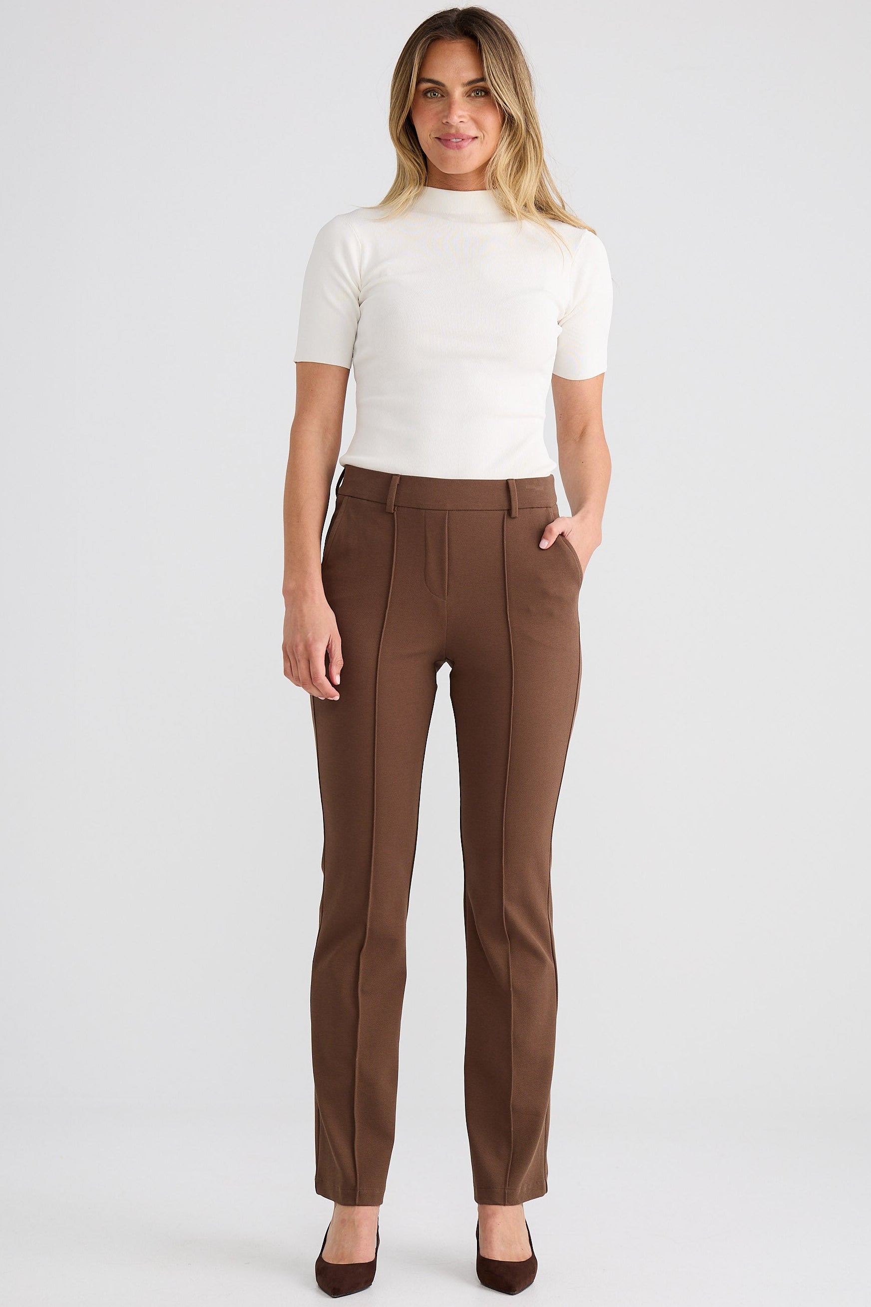 Woman wearing a white top and brown pants on a white background